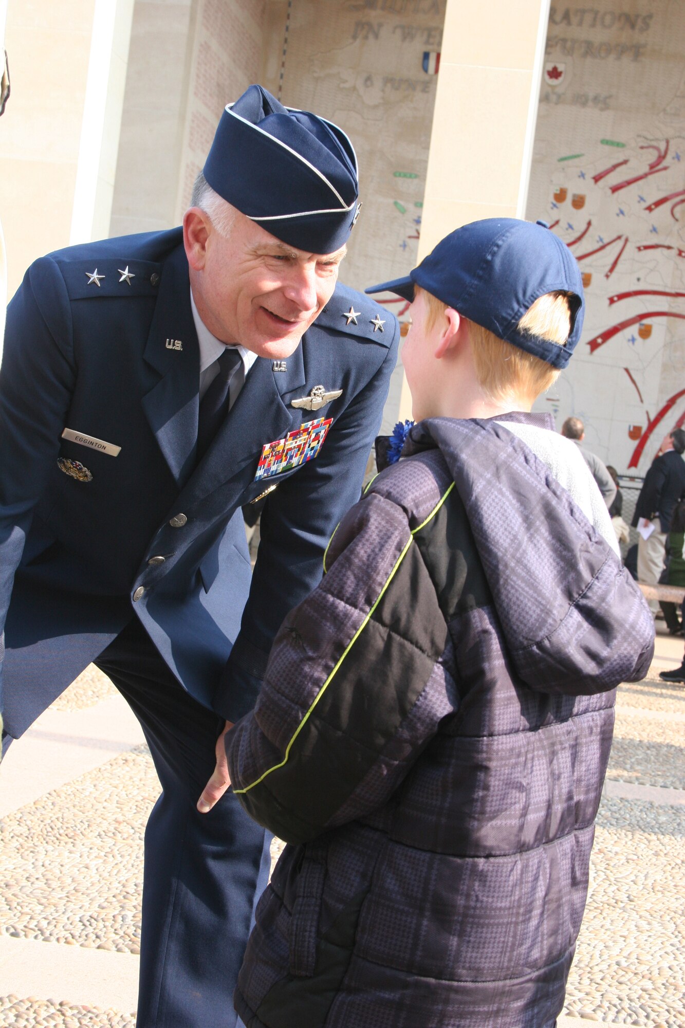 NORMANDY, France -- Maj. Gen. Jack Egginton, U.S. Air Forces in Europe director of operations, speaks with Zachary Shumaker, from Cub Scout Pack 97, Ansbach, Germany. Zachary explains to General Egginton that he just earned his Bear rank. General Egginton is the council president of the Boy Scouts of America Transatlantic Council and emceed the ceremony at the American Cemetery at Colleville sur Mer as part of the Boy Scouts' triennial Normandy Camporee. More than 3,000 people attended the event April 15-17, 2011. (U.S. Air Force photo/Lt. Col. Pamela A.Q. Cook)

