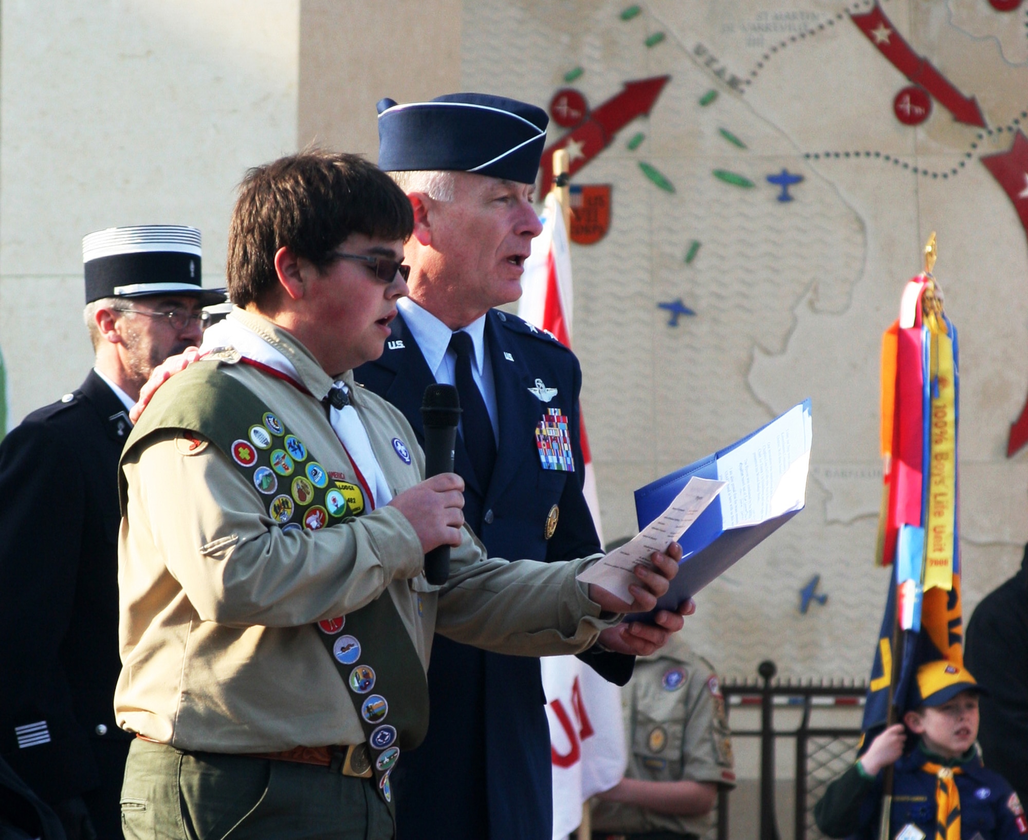 NORMANDY, France -- New Eagle Scout Victor Simpson from Troop 401 in London,  and Maj. Gen. Jack Egginton, U.S. Air Forces in Europe director of operations, sing "America the Beautiful" at the American Cemetery at Colleville sur Mer April 17, 2011. More than 3,000 Boy Scouts gathered in Normandy for the Boy Scouts of America Transatlantic Council’s triennial Normandy Camporee April 15-17 and concluded the campout with a ceremony honoring those buried at the cemetery overlooking Omaha Beach. (U.S. Air Force photo/Lt. Col. Pamela A.Q. Cook)
