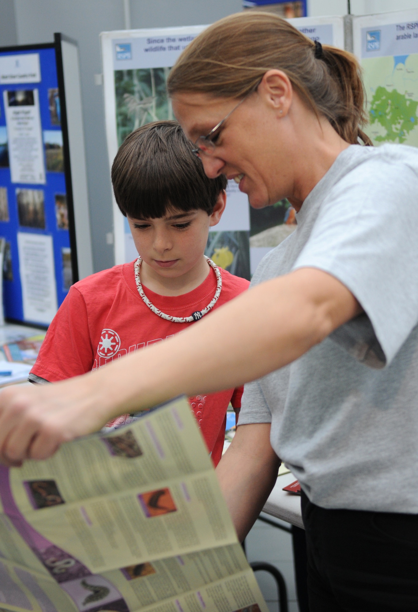 RAF MILDENHALL, England – Kole Greene (left), son of Lt. Col. Matt Greene, 100th Civil Engineer Squadron commander, looks at a poster with Mary-Ann Haberman, 100th CES environmental, during the Earth Week Fair at the Exchange here April 16, 2011. The fair included a face painting booth, quizzes for children, information booths and free educational materials. Earth Week is a week-long celebration of Earth Day between RAFs Mildenhall and Lakenheath. (U.S. Air Force photo/Airman 1st Class Rachel Waller)
