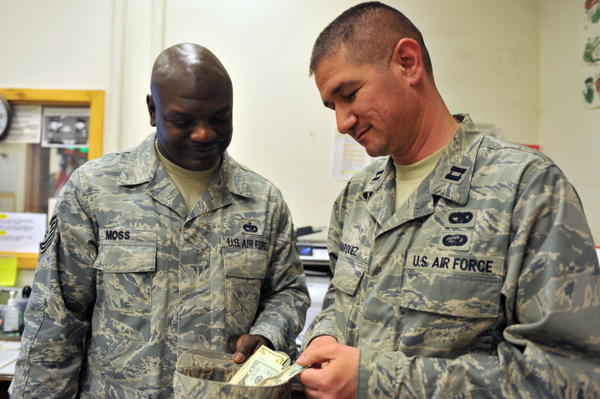 Tech. Sgt. Ladell Moss collects money from Capt. Charles Marquez, both assigned to the 455th Expeditionary Aerial Port Squadron, at Bagram Airfield, Afghanistan, April 14, 2011. (U.S. Air Force photo by Senior Airman Sheila deVera)