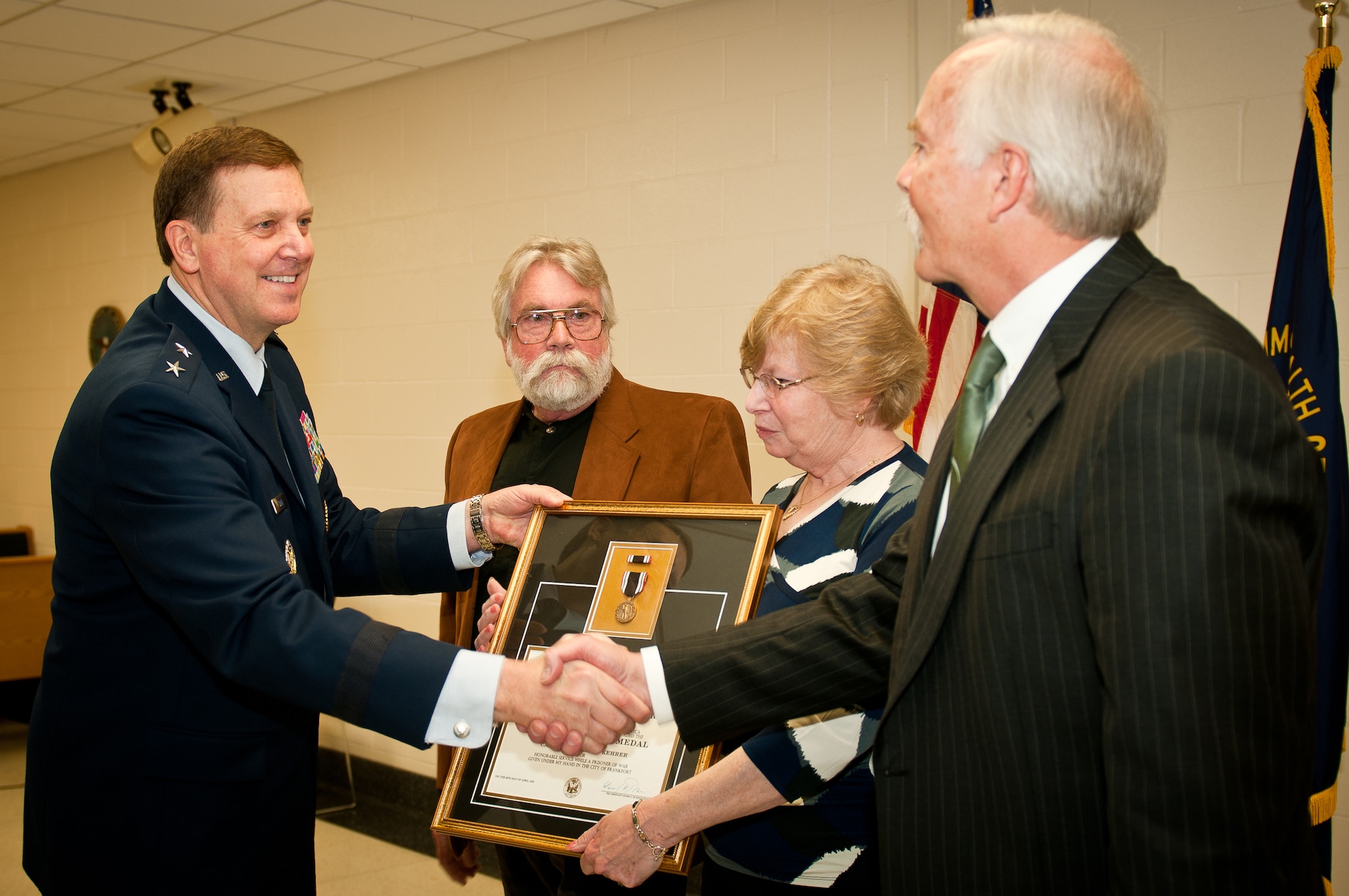 Maj. Gen. Edward W. Tonini, the Kentucky adjutant general, presents a posthumous Prisoner of War Medal to the sons and daughter of the late Capt. Merlin R. "Bob" Kehrer, a Kentucky Air National Guard pilot, during a ceremony April 16, 2011, at the Kentucky Air National Guard Base in Louisville, Ky.  Captain Kehrer was a young lieutenant and P-51 pilot in the U.S. Army Air Corps in World War II when his plane was shot down over enemy territory Feb. 24, 1944. He spent 13 months in a German prisoner of war camp. (U.S. Air Force photo/Tech. Sgt. Dennis Flora)