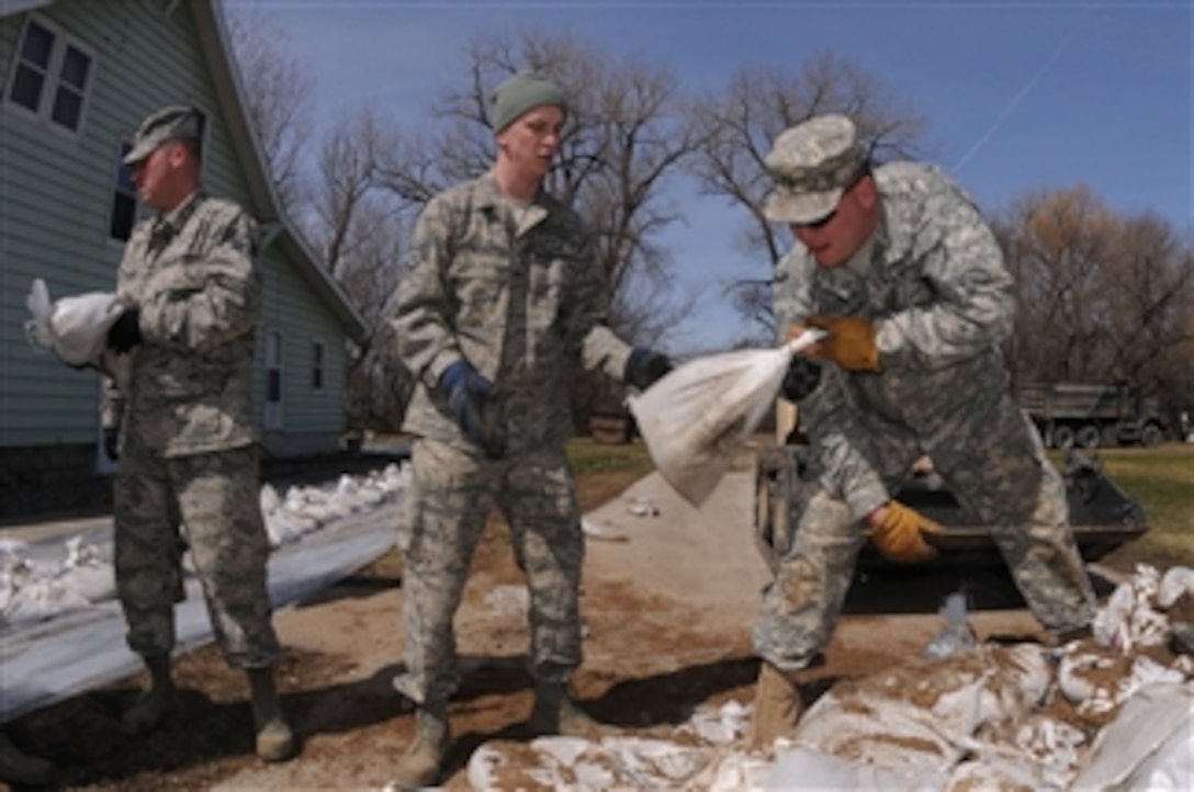 U.S. Air Force Senior Airman Casey Pritchard (left) and Staff Sgt. Sam Wagner, both with the 119th Civil Engineer Squadron, and Army Staff Sgt. Christopher Kleven (right), with the 1st Battalion, 188th Air Defense Artillery Regiment, pass sandbags to a North Dakota National Guard quick response force team near Kindred, N.D., on April 14, 2011.  The quick response force is comprised of soldiers and airmen, which responded to a request from a farm resident living along the Sheyenne River for sandbag assistance to create a flood levee to rising water around his house. More than 500 N.D. National Guard airmen and soldiers conducted flood operations in North Dakota, with the vast majority in Cass County.  