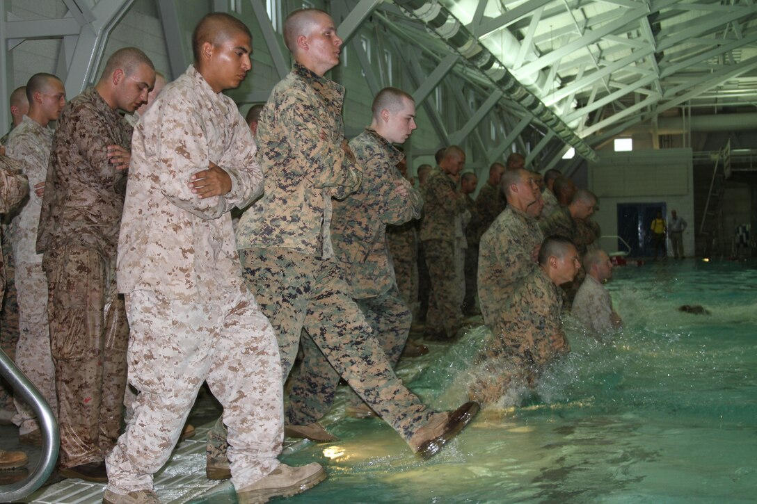 Recruits from Company E step into the water as part of the Marine Corps Water Survival Training Program April 18.  Co. E is the second company to qualify under the new requirements. Now there are only three different levels of qualification; basic, intermediate and advanced. The changes implemented  effective April 15 focus on making swim qualification more realistic. Marines are now required to wear the full camouflage uniform, including boots.