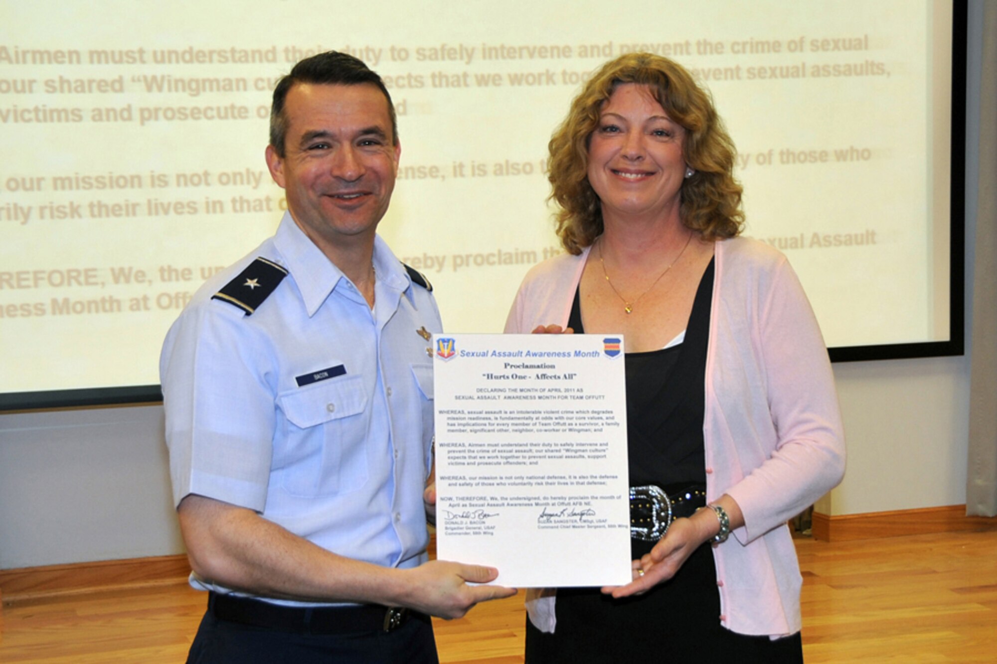 OFFUTT AIR FORCE BASE, Neb. -- Sharon Ingram, 55th Wing Sexual Assault Response Coordinator assistant, presents Brig. Gen. Donald Bacon, 55th Wing commander, with a proclamation to mark April as Sexual Assault Awareness Month. The SARC office has events planned throughout the month to educate and spread awareness to base personnel including three, “Can I Kiss You?” presentations by Mike Domitrz on Wednesday, April 27. For more information, please contact the SARC office at (402) 232-9999. (Photo by Jeff Gates)