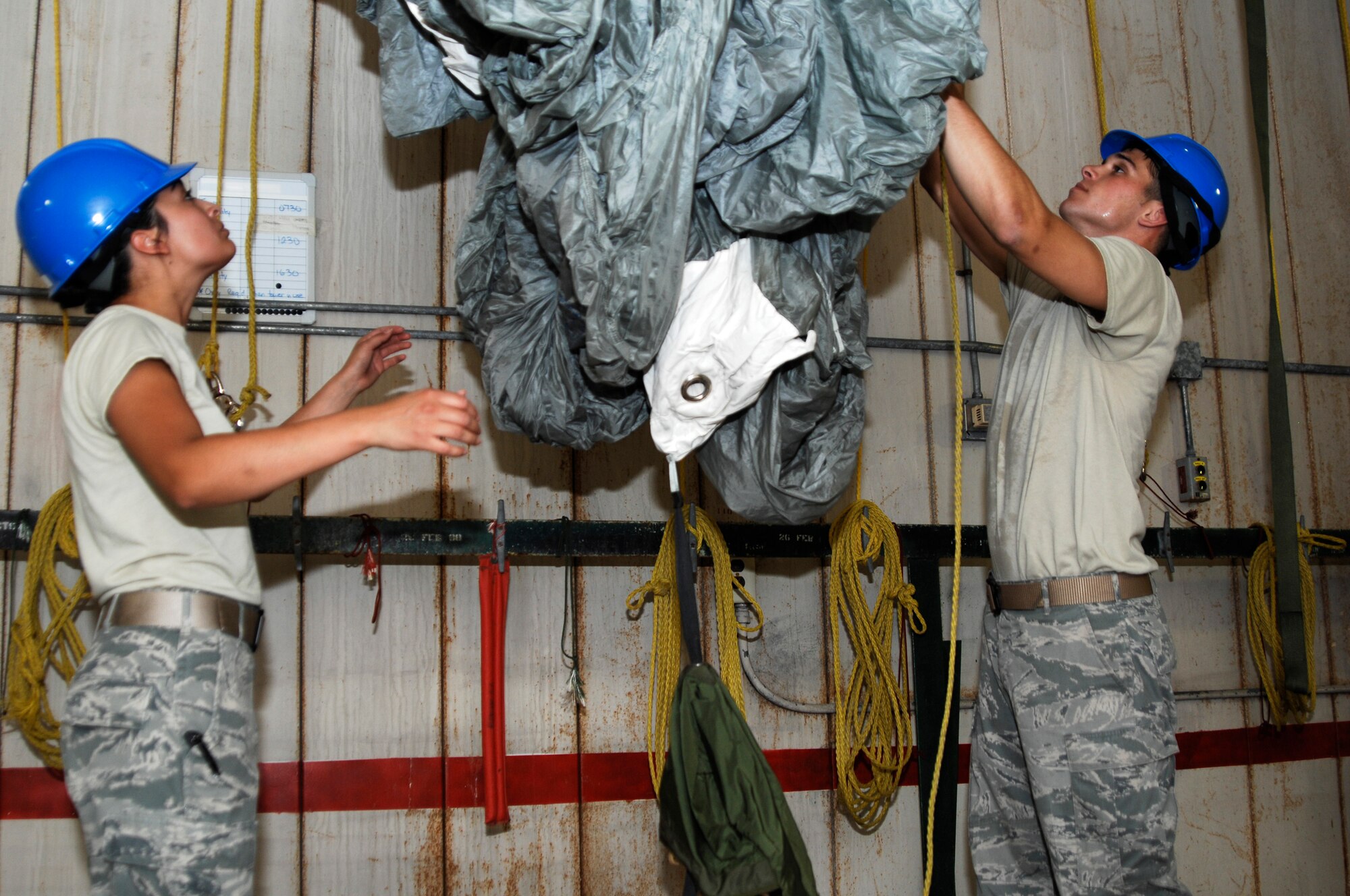 Senior Airmen Andrea Brandenburg and Roger Walters, 38th Rescue Squadron aircrew flight equipment journeymen, work together to take a parachute down after it’s done drying April 12 at Moody Air Force Base, Ga. After the parachutes are taken down, they are taken back to the AFE shop and repacked for another mission. (U.S. Air Force photo/Airman 1st Class Brigitte N. Brantley-Sisk)(RELEASED)
