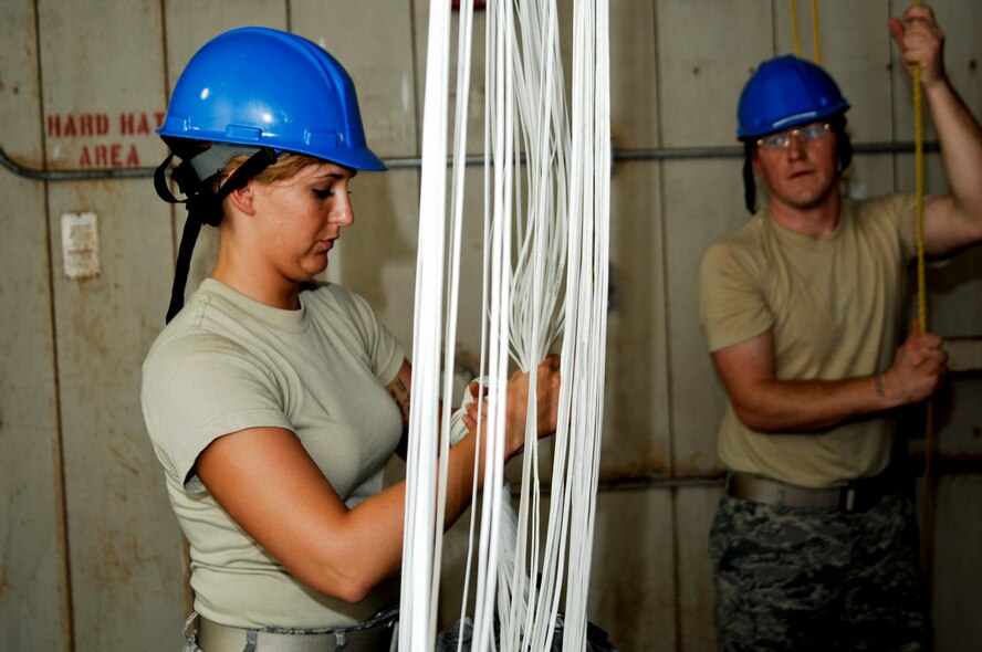 Airman 1st Class Caitlan Bunn, 38th Rescue Squadron aircrew flight equipment apprentice, daisy chains a parachute April 12 at Moody Air Force Base, Ga., after it has dried for four days. Since it was Airman Bunn’s first time taking down parachutes from the drying tower, she received on-the-job training from Staff Sgt. Clifford Sisk, her section’s NCO in charge. (U.S. Air Force photo/Airman 1st Class Brigitte N. Brantley-Sisk)(RELEASED)
