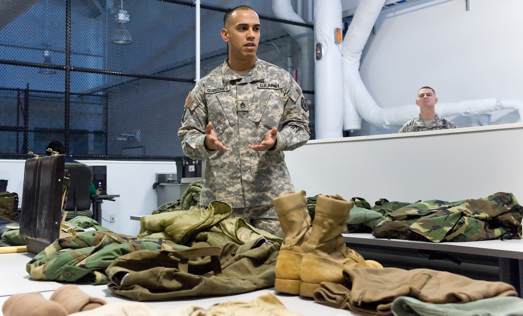 Army Staff Sgt. Luis Quinones speaks to the media about inventory process April 14, 2011, at the new Joint Personal Effects Depot at Dover Air Force Base, Del. The equipment displayed simulates the actual gear that is processed at JPED. (U.S. Air Force photo by Roland Balik)