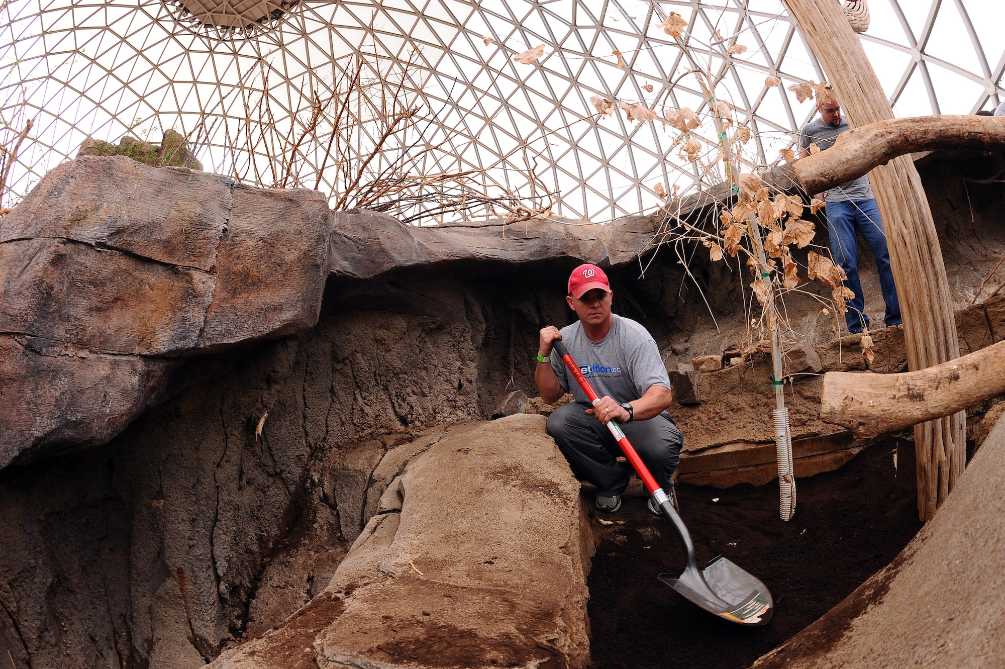 OFFUTT AIR FORCE BASE, Neb. - Staff Sgt. Jeremiah Sell, an aerospace ground equipment flying crew chief with the 55th Maintenance Squadron, takes a break from shoveling in fresh soil in the Desert Cottontail Rabbit planter box located inside Henry Doorly Zoo's Desert Dome, April 16. Maintenance of the exhibits is an annual chore performed by Offutt volunteers as part of the annual zoo cleanup event every spring. U.S. Air Force Photo by Josh Plueger (released)
