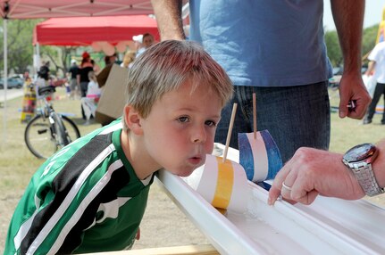 Connor Wisser, 5, blows hard to make a model sailboat move forward at a game booth during Famaganza  April 16 at Randolph Air Force Base, Texas. Connor is the son of Astrid and Lt. Col. Steve Wisser, with the 559th Flying Training Squadron. Famaganza featured games, prizes, dancing, a book fair and an Easter Egg Hunt. (U.S. Air Force photo/David Terry)
