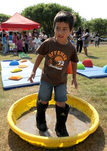 Elvin Cintron, 6, wears big boots to wade through a mud pit on the obstacle course at Famaganza  April 16  at Randolph Air Force Base, Texas. Elvin is the son of  Lillia and Capt.  Elvin Cintron, assigned to  U.S. Army South at Fort Sam Houston, Texas. (U.S. Air Force photo/David Terry)
