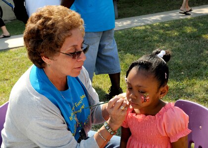 Arinna Bunton, 4, has her face painted by Sylvia Adams,Child Development Center, during Famaganza April 16 at  Randolph Air Force Base, Texas. Arinna is the daughter of Army Private Monet Bunton who is assigned to  Fort Leonard Wood, Mo.(U.S. Air Force photo/David Terry)