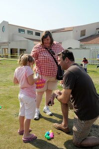 Capt. Scott Strater helps his daughter Mya, 6, check for prizes in Easter eggs she found during the April 16  Easter egg hunt sponsored by Youth Programs at Randolph Air Force Base, Texas. Sheryl Maddux, Mya's aunt, also helps check for the prizes. Captain Strater is assigned to the 59th Medical Wing at nearby Lackland Air Force Base.(U.S. Air Force photo/David Terry)