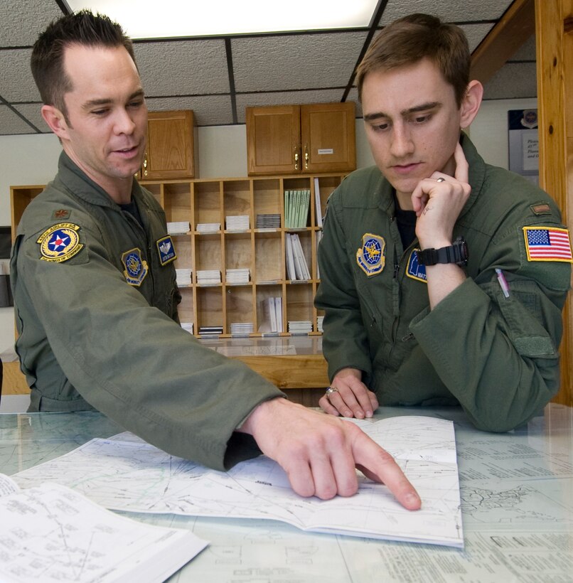 Major Justin Watson, left, 457th Airlift Squadron chief evaluator pilot, and 2nd Lt. Matt Williams, first pilot, review a flight route for an upcoming mission April 15. (Photo by Bobby Jones)
