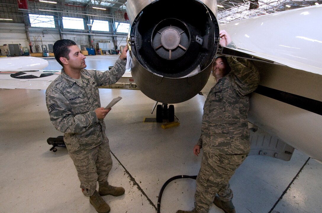 Staff Sgt. Rafael Madrigal, 457th Airlift Squadron quality assurance representative, left, and Tech. Sgt. Scott Reel, 457 AS quality assurance representative, inspect the engine thrust reverser switches on a squadron C-21 aircraft April 15. (Photo by Bobby Jones)
