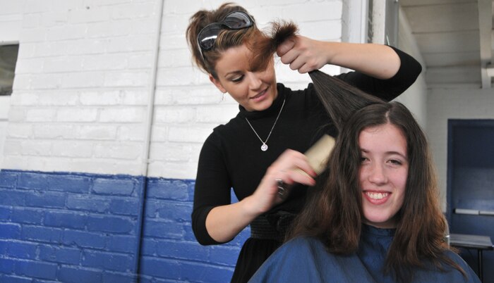 Navy wife, Kira Reynolds, receives a free hair cut by a volunteer cosmetologist April 19, at Armory Park in North Charleston, S.C. Volunteer cosmetologists and makeup artists pampered military wives as part of the military spouse make-over event hosted by The Look for Success non-profit organization. (U.S. Air Force photo /A1C Jared Trimarchi)
