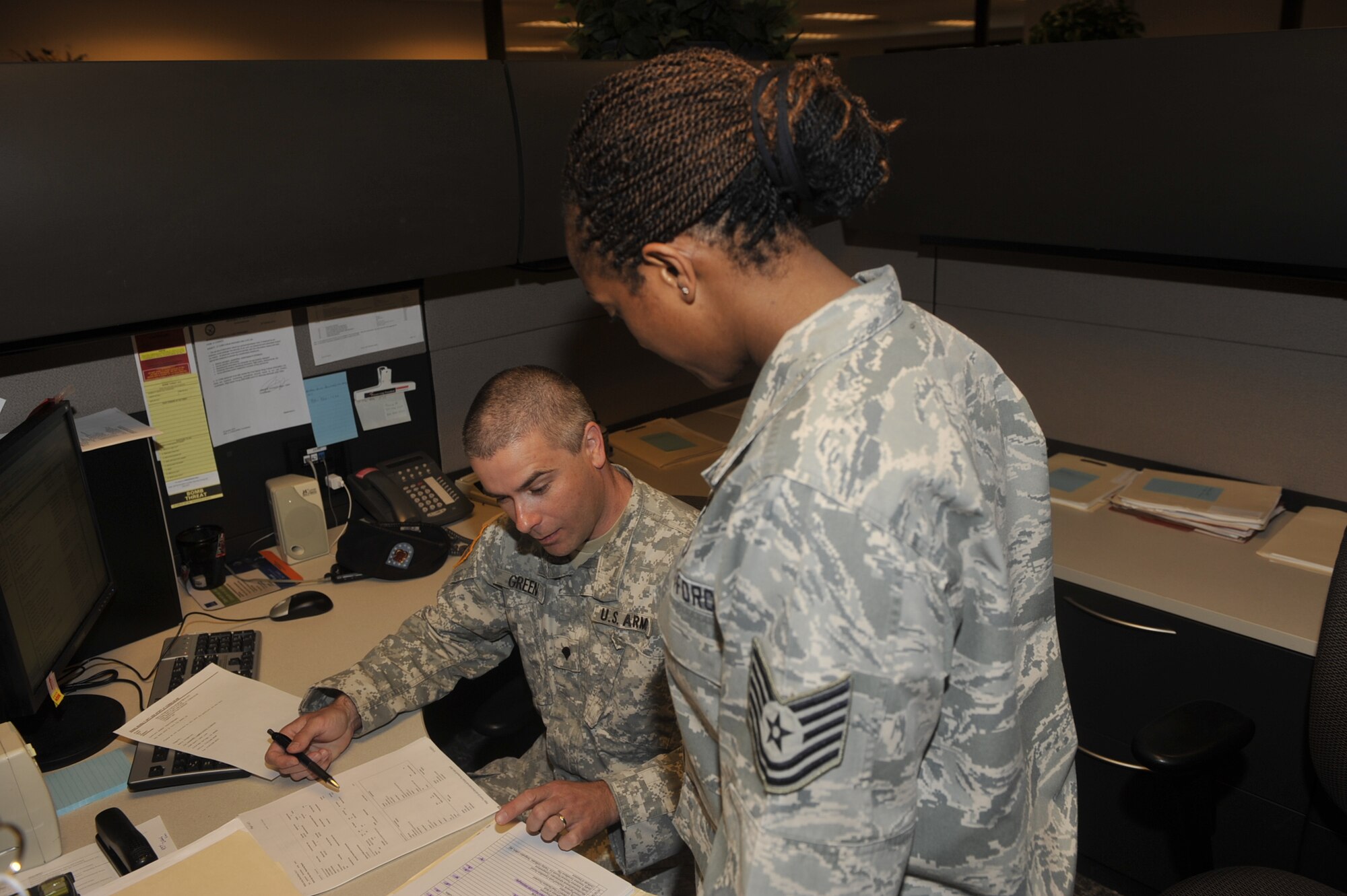 Spc. Bobby Green, from Fort Carson, looks over contracts with Tech. Sgt. Shannell Long, 21st Contracting Squadron contract specialist, April 14, 2011, on Peterson Air Force Base. Specialist Green is working with the 21st Contracting Squadron through a Department of Defense program Operation Warfighter, which places wounded services members in temporary work assignments while they convalesce or await the results of a medical review board. Specialist Green was injured during a deployment downrange and is in the Disability Evaluation System. Meanwhile, he has discovered a knack for contracting and would like to pursue contracting as a career in the civilian workforce. The 21st Contracting Squadron has five service members working for them through the program. (U.S. Air Force photo/Robb Lingley) 
