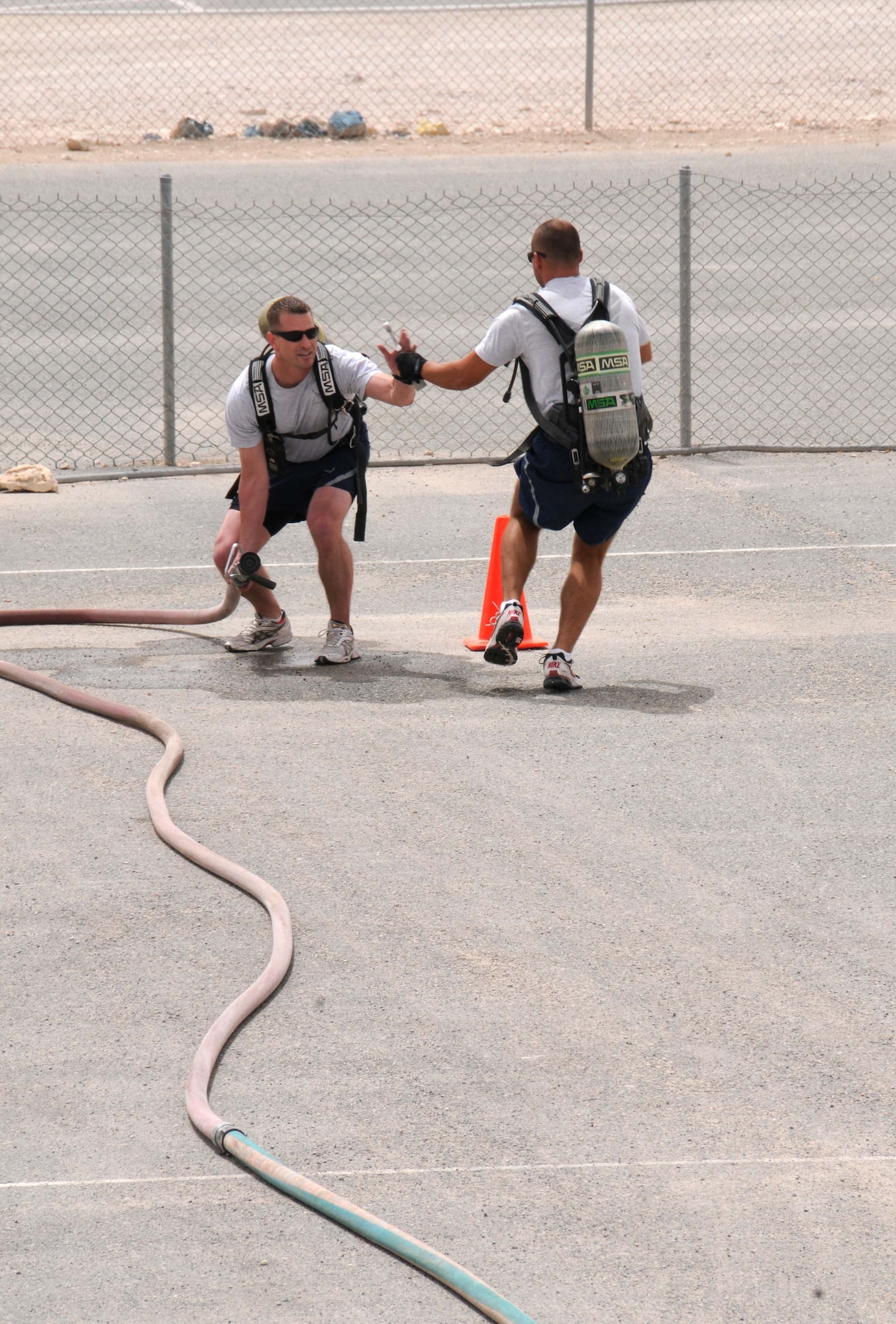 Senior Airman Nathan Nowakowski passes off the baton to Master Sgt. Phil Altpeter April 16 in Southwest Asia. Both are from the 379th Expeditionary Logistics Readiness Squadron and were among many other Airmen that participated in the Fire Muster that was held by the 379th Expeditionary Civil Engineer Squadron. (U.S. Air Force photo/Staff Sgt Anthony Graham)