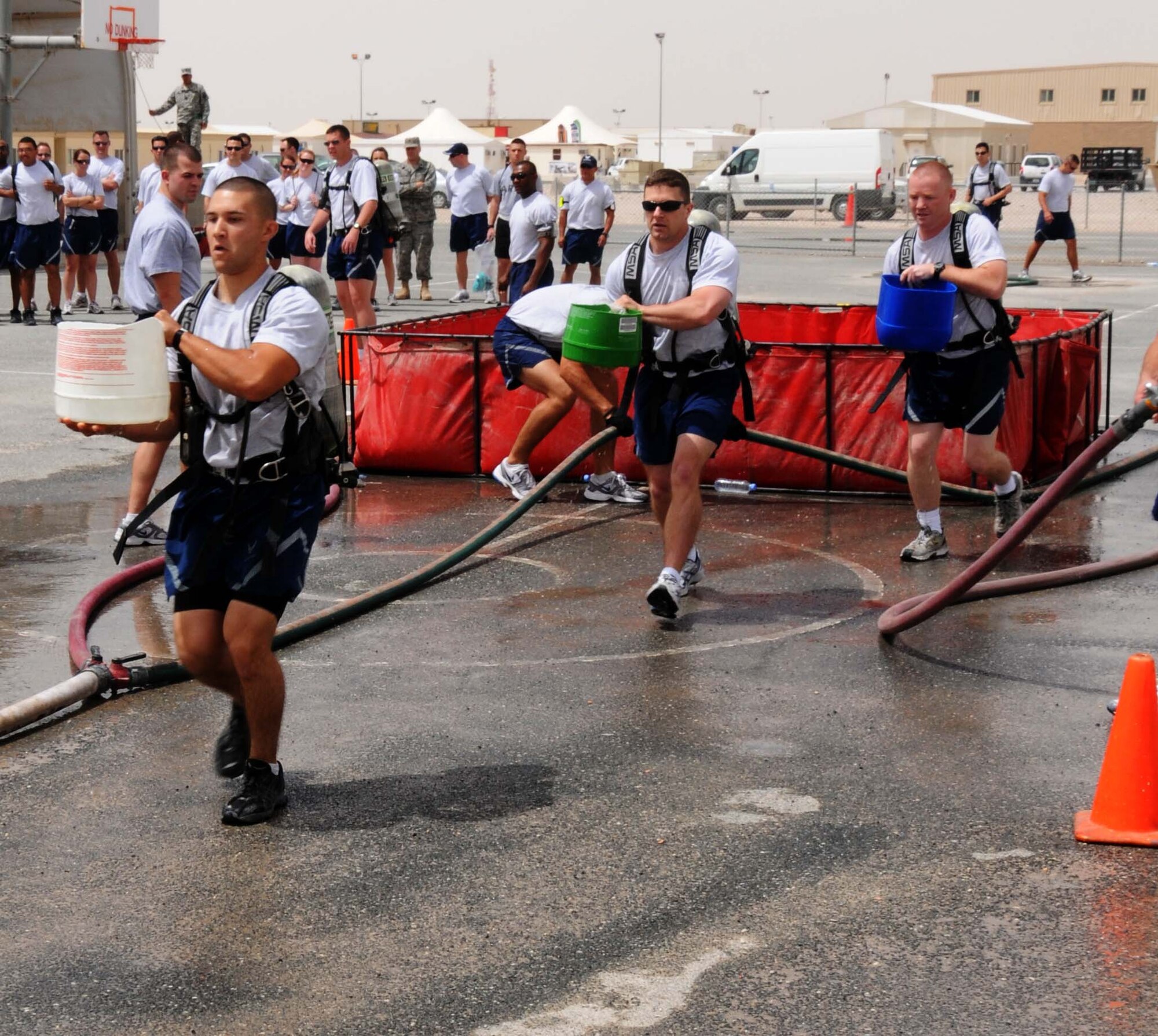 Airman 1st Class Tyler Crawford, Staff Sgt. Martin Schoffstall and 1st Lt. Evan Gigas, all from the 379th Expeditionary Communications Squadron, carry buckets of water in the bucket brigade during the Fire Muster April 16 in Southwest Asia. The Muster is held every rotation by the 379th Civil Engineer Squadron. (U.S. Air Force photo/Staff Sgt Anthony Graham)
