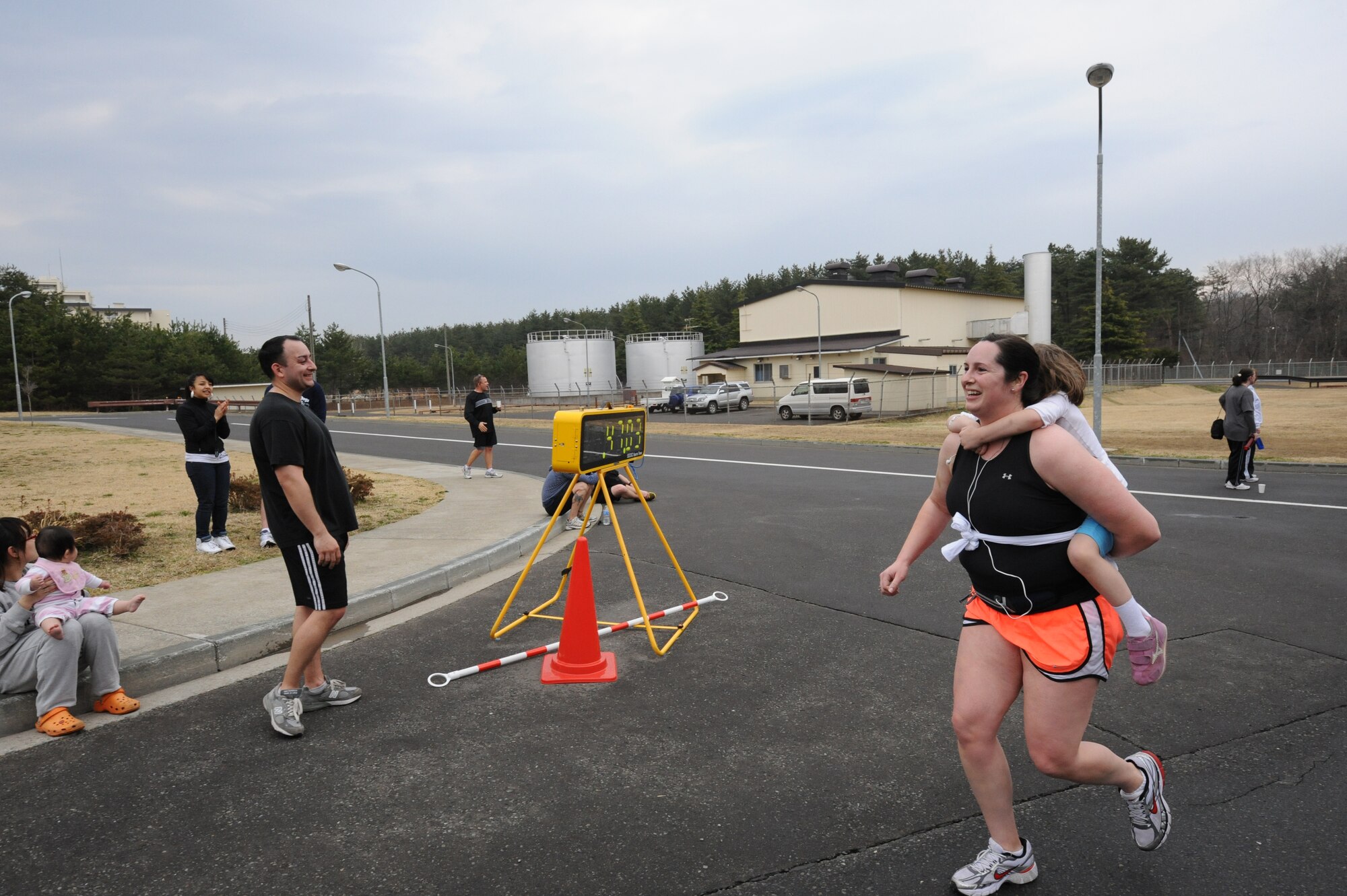 MISAWA AIR BASE, Japan ? Capt. Heather McDaniel, 35th Logistics Readiness Squadron, ran across the finish line of the Sakura 5 Miler fun run with her daughter Catherine, 4, on her back 16 April.  The Sakura 5 Miler was the first run of the season held by 35th Force Support Squadron and had more than 200 participants.  (U.S. Air Force Photo by Staff Sgt. April Quintanilla/Released)