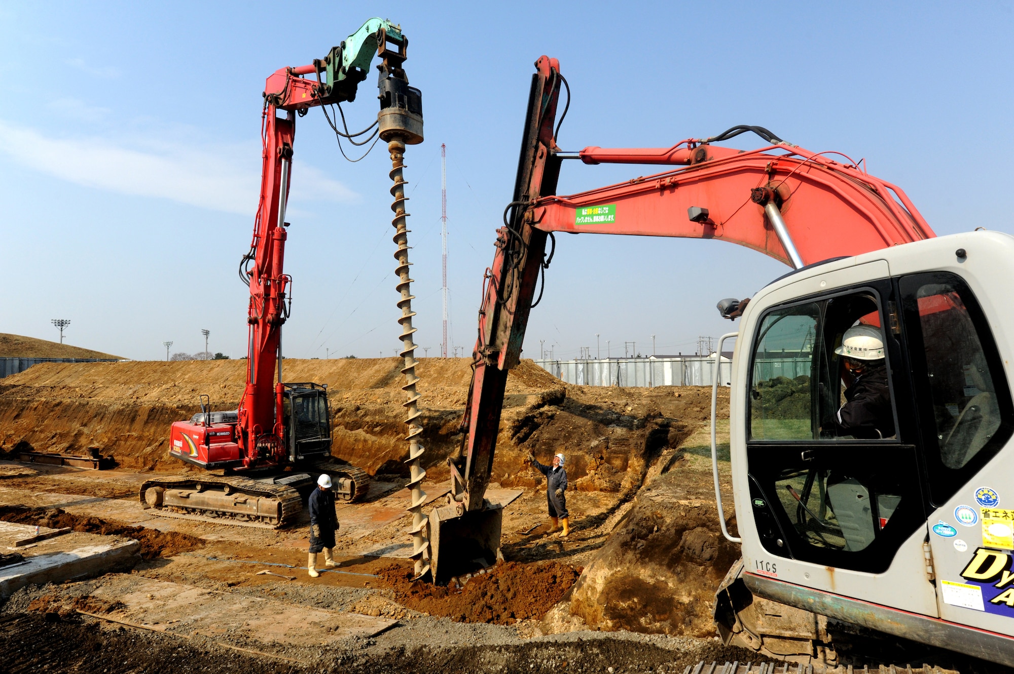 MISAWA AIR BASE, Japan -- A track hoe removes dirt as an auger drills into the area around a 158,000 gallon underground tank behind Edgen High School 14 April. The 35th Civil Engineer Squadron's project was necessary to remove any old and unnecessary infrastructure, which may cause potential hazards.  (U.S. Air Force Photo by Staff Sgt. April Quintanilla/Released)