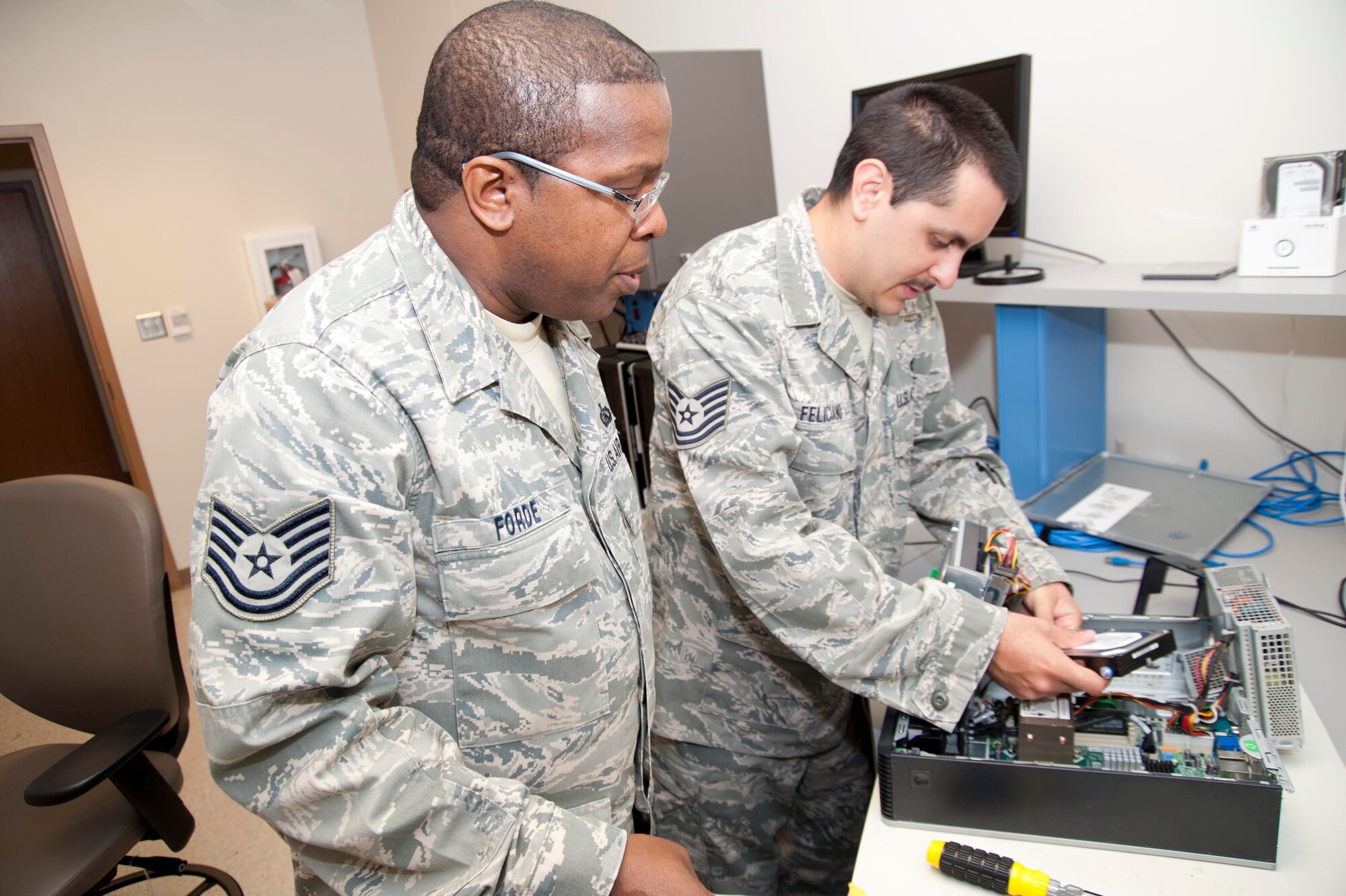 Tech. Sgts. Vernon Forde (left) and Steven Feliciano, 403rd Communications Flight cyber systems operators, service a wing computer in the Network Training Work Center. Members from various communications career field use the lab to hone their computer networking and routing skills. (U.S. Air Force photo by Tech. Sgt. Ryan Labadens)