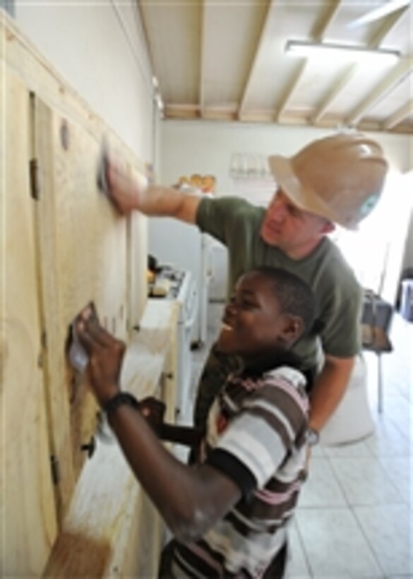 Sgt. Peter Swigart and a local child sand newly built cabinets at Trenchtown Primary School in Kingston, Jamaica, during a Continuing Promise 2011 community service project on April 17, 2011.  Continuing Promise is a five-month humanitarian assistance mission to the Caribbean, Central and South America.  