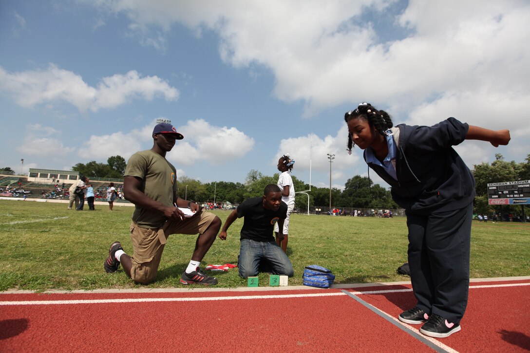 Pfc. Christian Lloyd and Cpl. Morris Blackmon, Marine Forces Reserve volunteers , watch as a competitor takes her turn at the long jump during the Orleans Parish Track and Field Special Olympics Meet April 29 in Algiers, LA. MarForRes volunteers helped demonstrate activities, keep score and measure performances as nearly 300 athletes with cognitive and physical disabilities competed against one another at Behrman Stadium.