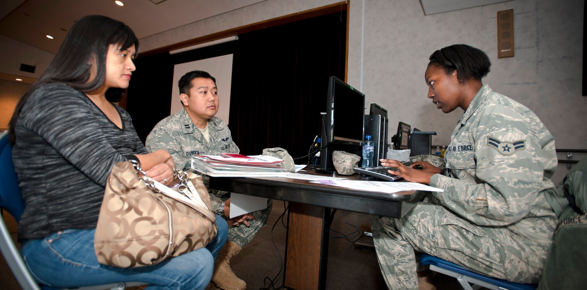 YOKOTA AIR BASE, Japan -- Airman 1st Class Carmen Turner, 374th Comptroller Squadron finance representative, helps Maria Dungca, wife of Capt. Jay Dungca, with her travel voucher at a ReStart briefing at the Airman & Family Readiness Center here April 21. Ms. Dungca recently returned from California after the voluntary authorized departure order was lifted. (U.S. Air Force photo/Staff Sgt. Chad C. Strohmeyer)