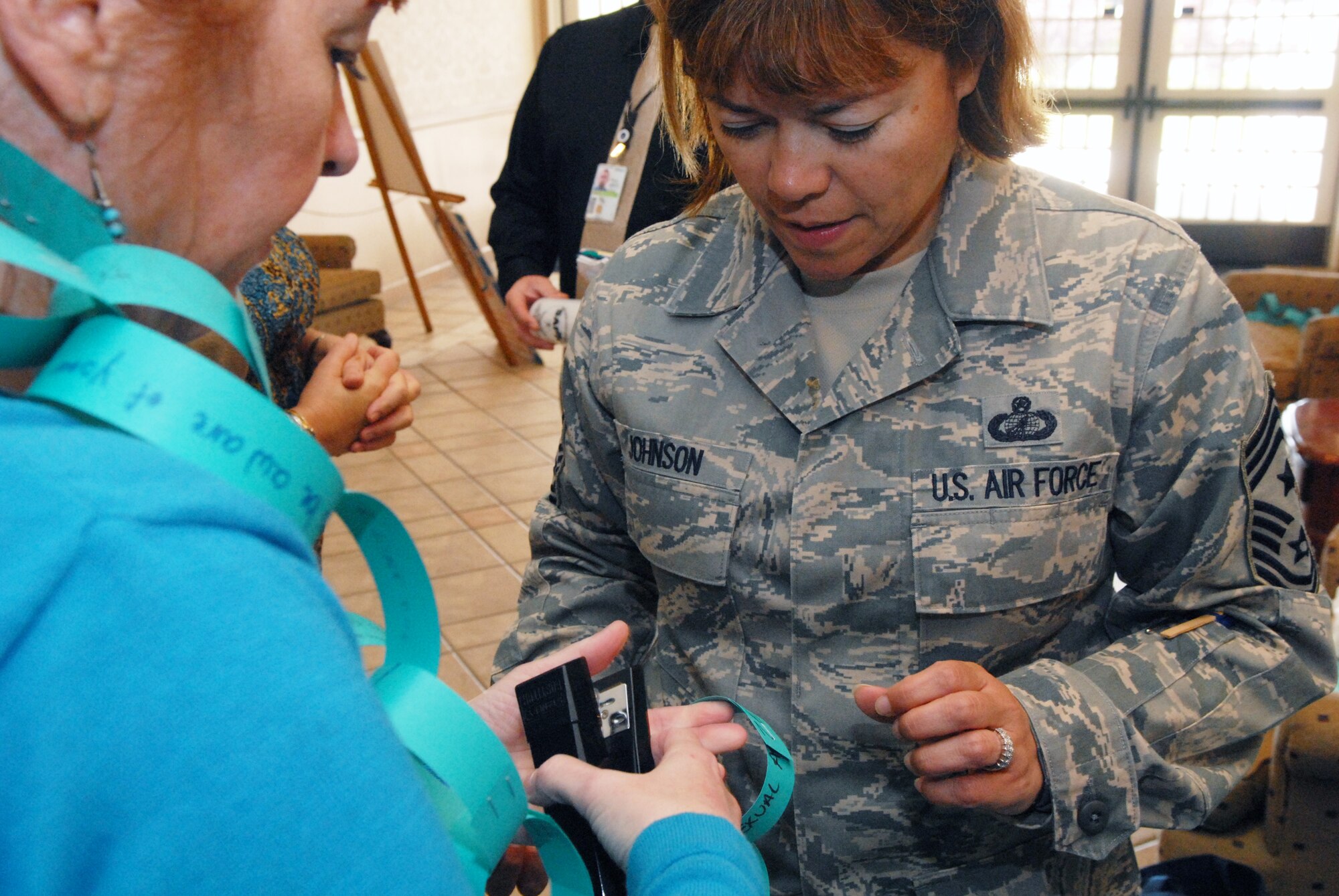 VANDENBERG AIR FORCE BASE, Calif. -- Susan Haury, Sexual Assault Prevention and Response assistant, helps Chief Master Sgt. Angelica Johnson, 30th Space Wing command chief, add a link to the Link and Think chain during a SARC promotional event here Wednesday, April 20, 2011, in the Pacific Coast Club. The SARC team’s mission is to reinforce the Air Force's commitment to eliminate incidents of sexual assault through a comprehensive policy centering on awareness and prevention, training and education, victim advocacy, response, reporting, and accountability.  (U.S. Air Force photo/Jerry E. Clemens, Jr.)



