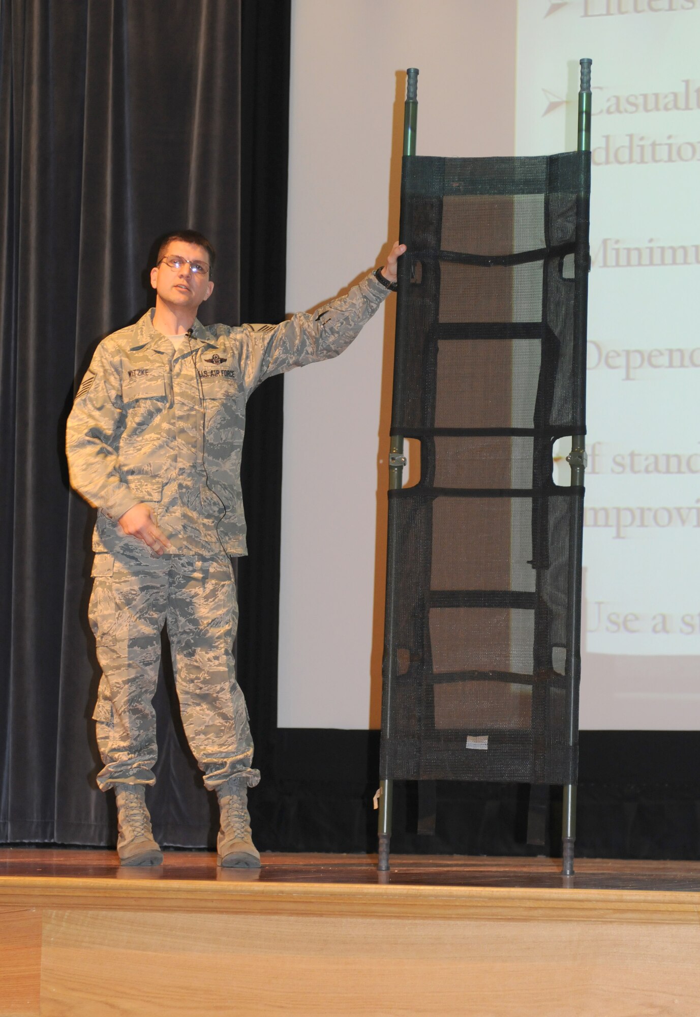 Master Sgt. John Witzke, 709th Airlift Squadron, instructs a crowd of about 250 512th Airlift Wing members on the proper use of a litter in preparation for an Operational Readiness Inspection in December. In addition to being a flight engineer, Sergeant Witzke is a military Self Aid and Buddy Care instructor and an emergency medical technician in his civilian capacity. (U.S. Air Force photo by Capt. Marnee A.C. Losurdo/Released)
