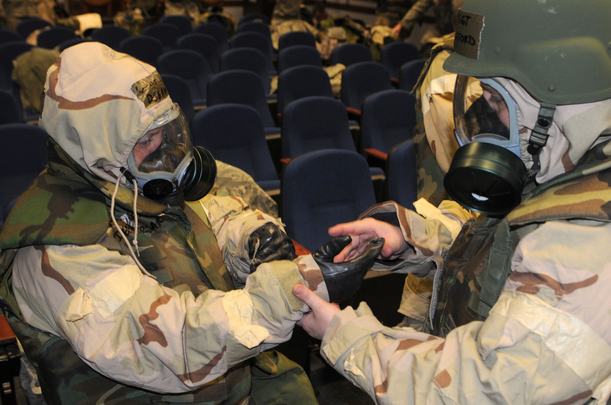 Senior Master Sgt. Dee Priar (left) and Master Sgt. Joy Clifford, both of the 512th Financial Management Office, use the buddy system while donning their Mission Oriented Protective Posture gear during an exercise April 16 at the 3rd Airlift Squadron. Individuals have two minutes to convert from MOPP level 2 to MOPP level 4. (U.S. Air Force photo by Capt. Marnee A.C. Losurdo/Released)
