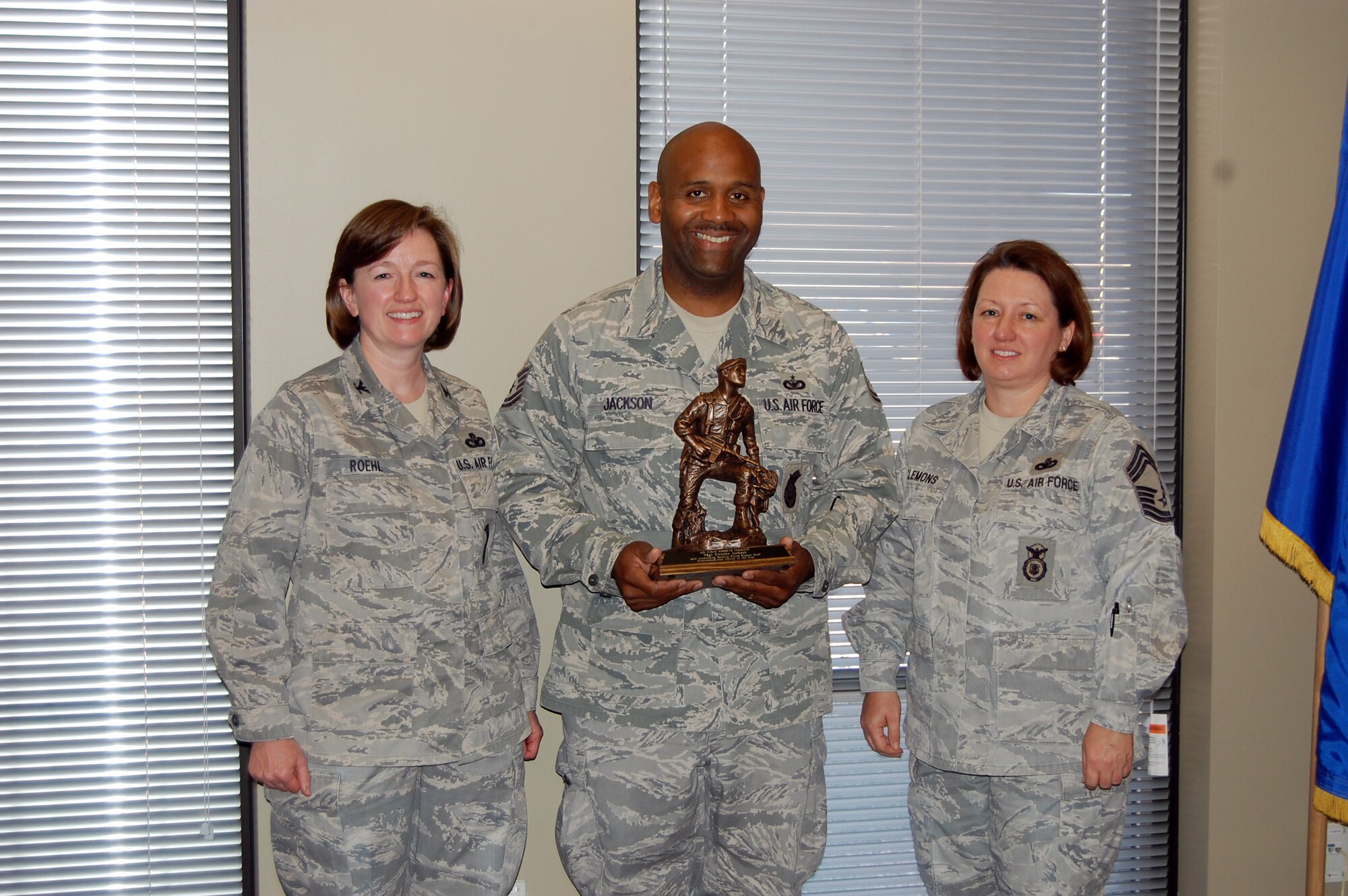 NELLIS AIR FORCE BASE, Nev. -- (Center) Tech. Sgt. Dwayne Jackson, 926th Group antiterrorism officer and security manager, is presented with the Air Force Reserve Command's Security Forces Staff Noncommissioned Officer of 2010 award by Col. Mary Roehl, AFRC's Top Cop, and Chief Master Sgt. Suzanne Clemons, AFRC's chief of training and combat arms, here April 1. (U.S. Air Force photo/Capt. Jessica Martin)