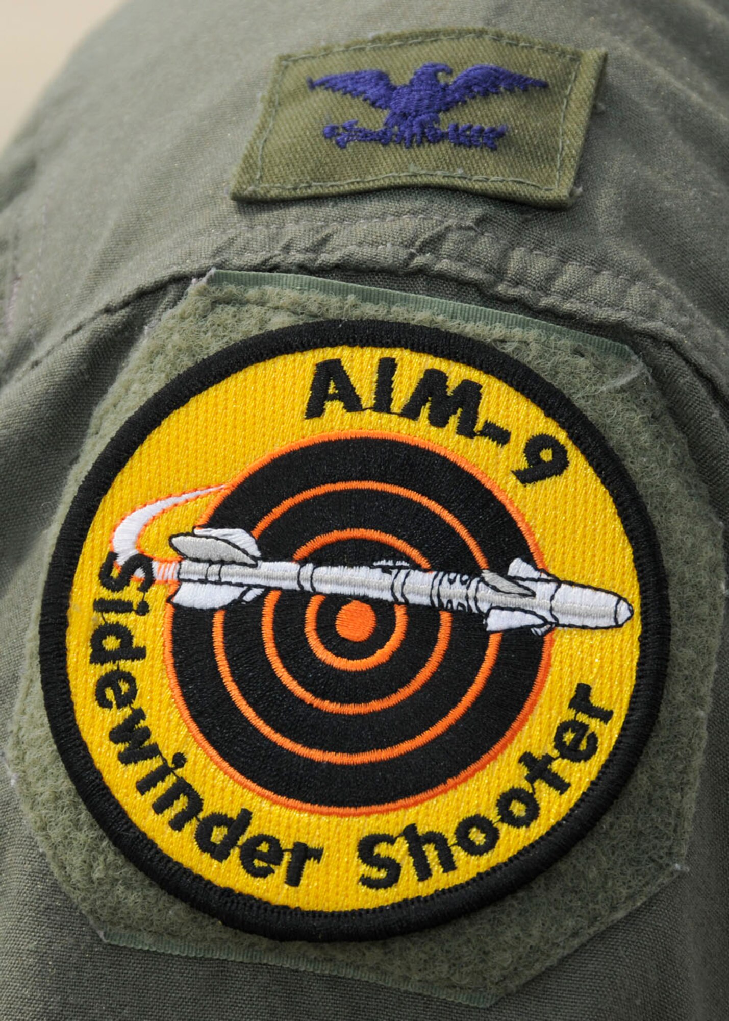 A newly achieved AIM-9 Sidewinder Shooter patch worn my Col. Kenneth Lambrich from the 104th Fighter Wing, Massachusetts Air National Guard as he watches maintenance crews work on the F-15 at Tyndall AFB, Florida as they participate in the Weapons System Evaluation Program (WSEP), known as Combat Archer, on April 19, 2011. This training is important for the ground crews to test their maintenance systems and processes while loading live munitions on the F-15 eagle, as well as critical live war fighting training for the F-15 pilots to employ air-to-air missiles against real world targets.  (U.S.A.F. photograph by Senior Master Sgt. Robert J. Sabonis)