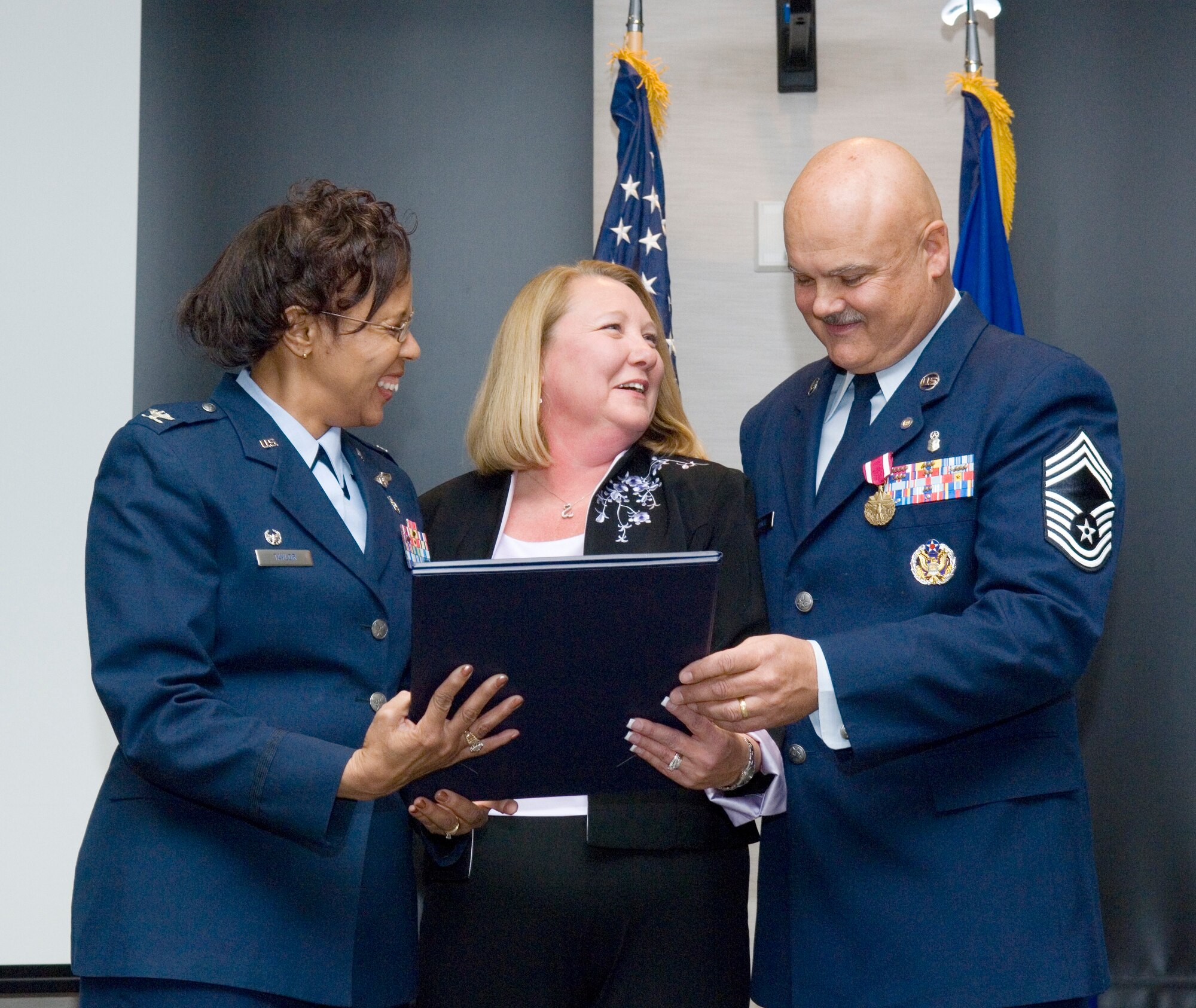 Chief Master Sgt. David Gilmore, 95th Medical Group superintendent, presents his wife, Donna, (center) with a Spouse Certificate of Appreciation during his retirement ceremony in the Conference Center, April 15. Col. Janet Taylor, 95th MDG commander, joins Chief Gilmore as he retires from the Air Force after 30 years of service to his country. (Air Force photo by Rob Densmore)