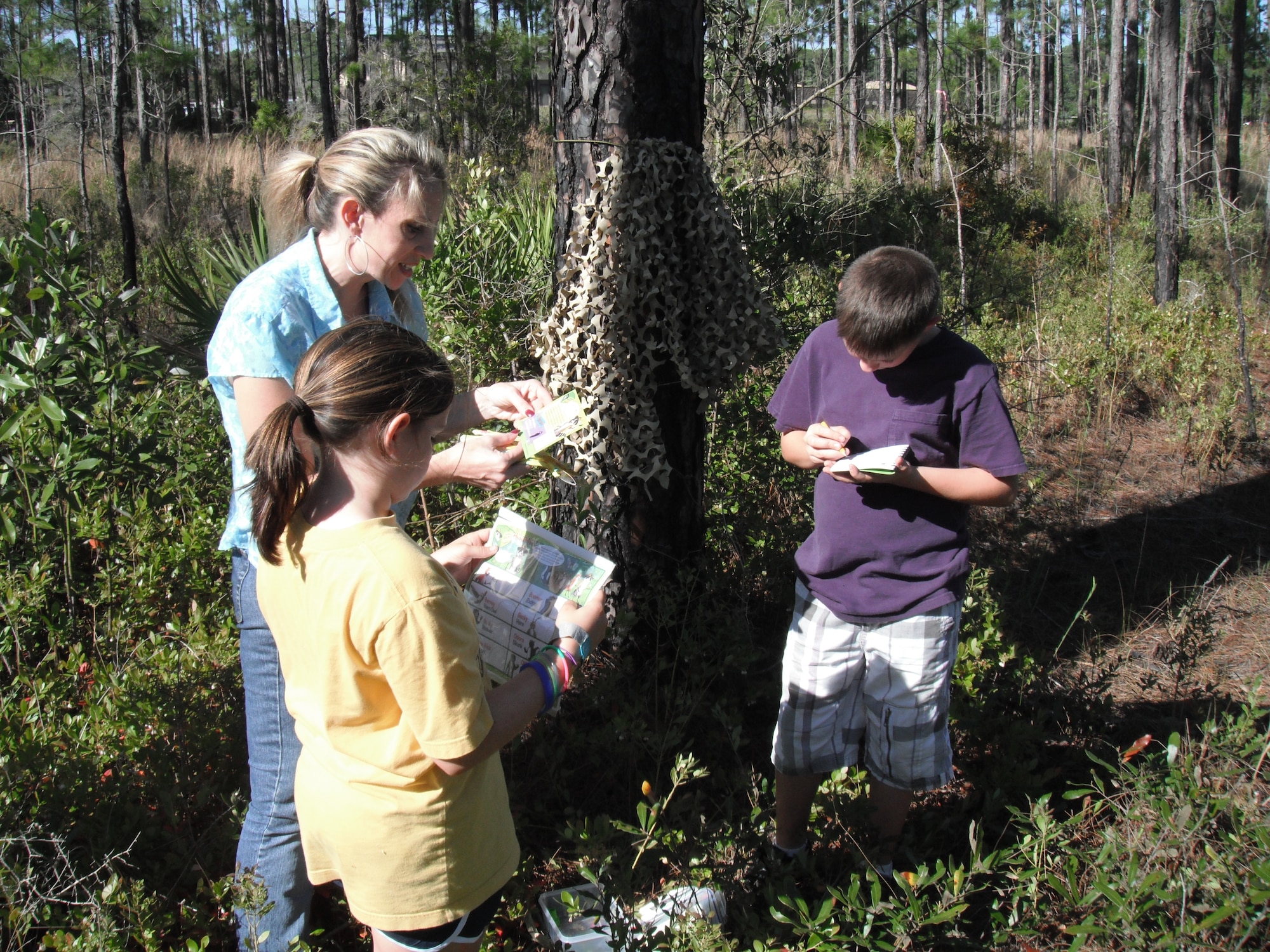 The Caylor family (left to right), Kimberly, Peyton (10) and Tyler (11), go through the first location’s box during the Hurlburt Field Library’s Ranger Rick Program on Hurlburt Field, Fla., Apr. 16, 2011.  The Ranger Rick Program is a geocaching outdoor education program with three locations scattered around base. (U.S. Air Force photo/Master Sgt. Steve Caylor)