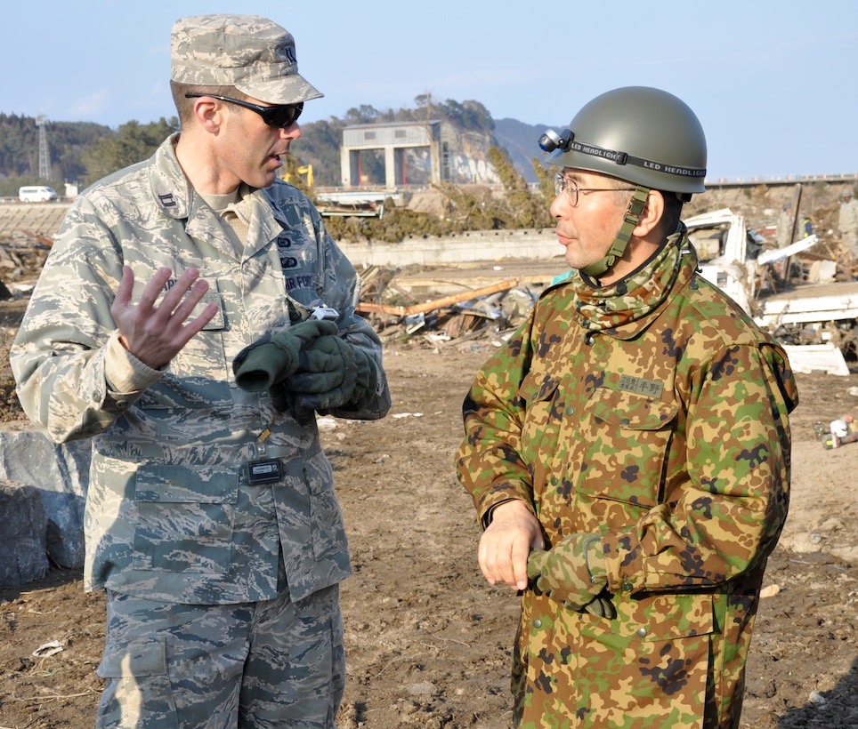 U.S. Air Force Capt. Tyler Harrris, an executive officer with the 373th Intelligence, Surveillance and Reconnaissance Group from Misawa Air Base, and a Woods Cross, Utah-native, speaks with Japanese Self-Defense Force Col. Takeshi Hirano, 26th Regiment commander, in a tsunami-stricken area here in Iwate Prefecture, Japan to support Operation Tomodachi March 29. More than 1,500 volunteers have worked nearly 17,000 hours providing clean-up efforts in the Japanese community since the devastating earthquake and tsunami March 11.