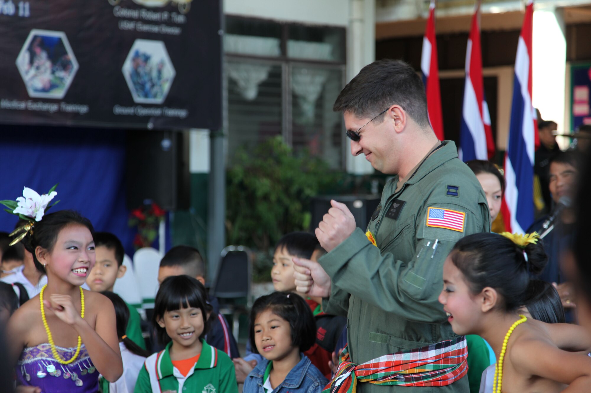 UDON THANI, Thailand -- Capt. James Demis, a pilot with the 1st Special Operations Squadron, laughs as he dances with children during a visit to the Songtam Witthaya School here Jan. 31. Airmen from the 353rd Special Operations Group joined Royal Thai Air Force members on a visit to the school to donate school supplies and sporting goods. During the visit, children from the school treated the U.S. and Royal Thai Air Force members to musical performances and dances. (Courtesy photo)