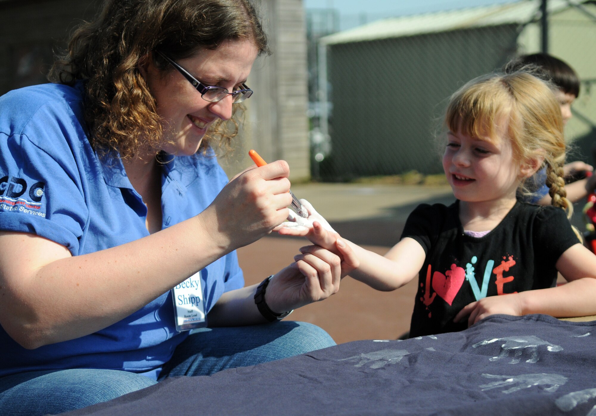 RAF MILDENHALL, England -- Becky Shipp, a caregiver at the RAF Mildenhall Child Development Center, paints Caelyn’s, daughter of Krysten Glab, a caregiver at the RAF Mildenhall CDC, hand during an Earth Week event at the CDC April 19, 2011. Children from the CDC made t-shirts and planted plants in honor of Earth Week. This is a week-long celebration of Earth Day between RAFs Mildenhall and Lakenheath. The first Earth Week was celebrated 14 years ago. (U.S. Air Force photo/Airman 1st Class Rachel Waller)