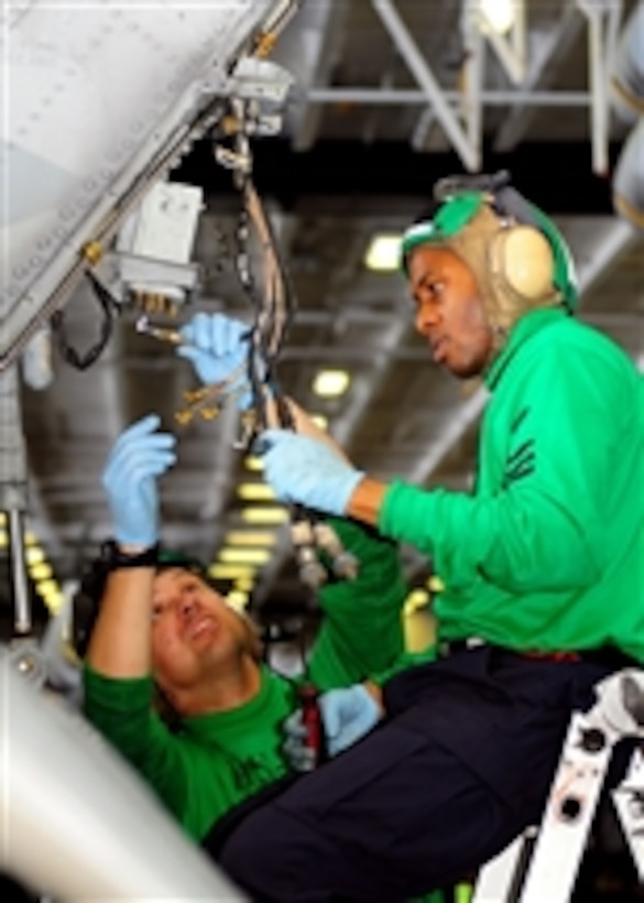 Petty Officer 1st Class William Schuyler (right) and Petty Officer 1st Class Jason Siani, both assigned to Anti-Submarine Helicopter Squadron 4, repair components of a radar warning system on a helicopter in the hangar bay aboard the aircraft carrier USS Ronald Reagan (CVN 76) in the Pacific Ocean on April 16, 2011.  