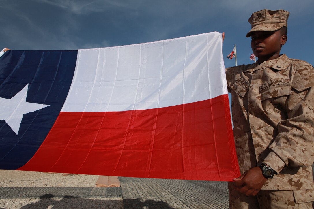 Lance Cpl. Alicia D. McGinnis, a supply clerk with Marine Wing Headquarters Squadron 2, holds the Texas state flag during a remembrance ceremony held for San Jacinto Day at the 2nd Marine Aircraft Wing (Forward) headquarters compound on Camp Leatherneck, Afghanistan, April 21. San Jacinto Day commemorates a battle between the Texas Army and Mexican forces and is considered the turning point for Texas' independence from Mexico, April 21, 1836. “The ceremony gave me a sense of pride in the place I call home,” said McGinnis, a native of Houston.