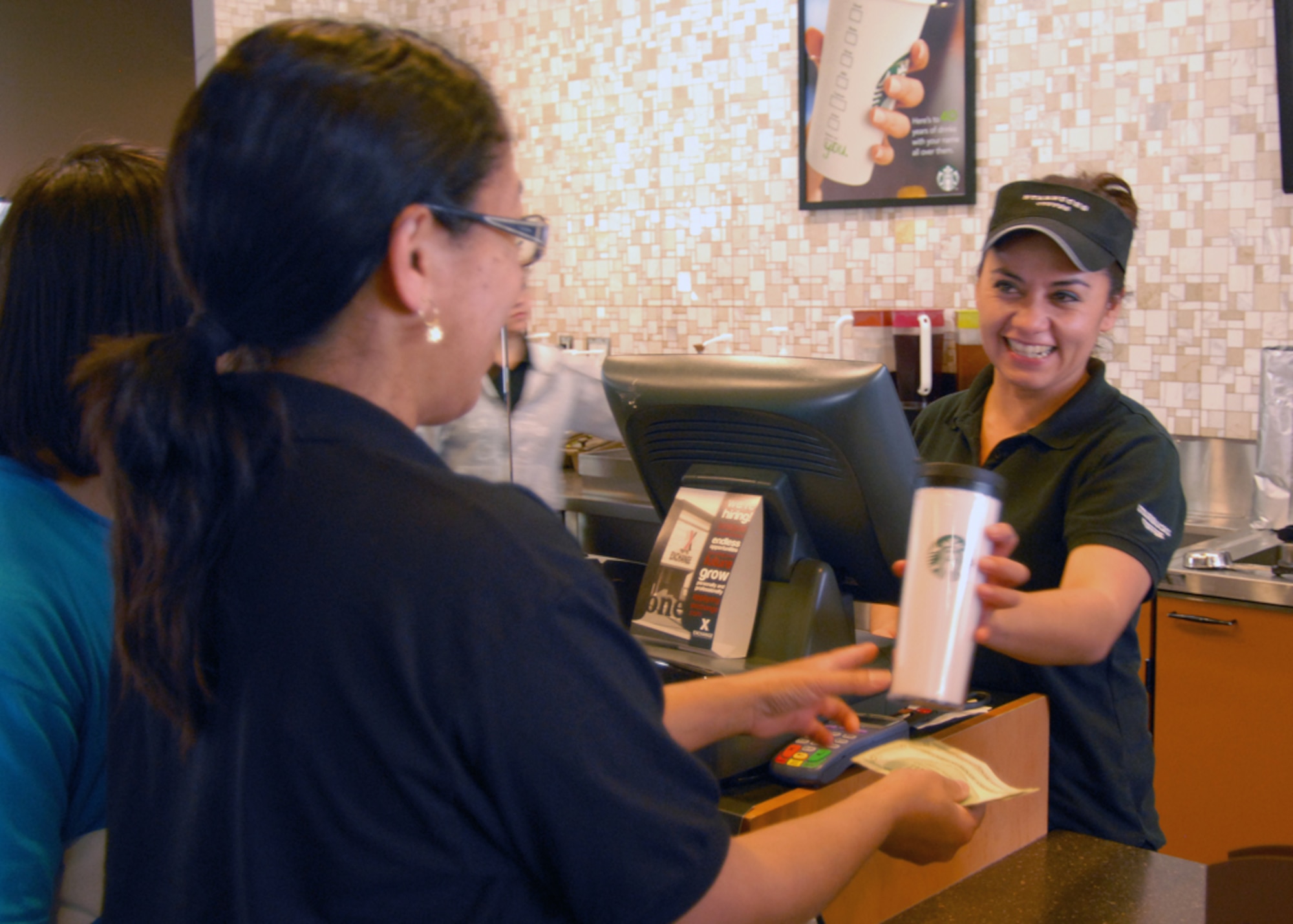 Alma Peña, Edwards Starbucks manager, informs a customer of the free coffee special being offered on Earth Day if patrons bring in their own coffee mug to the Edwards Starbucks location. (U.S. Air Force photo by Jet Fabara)