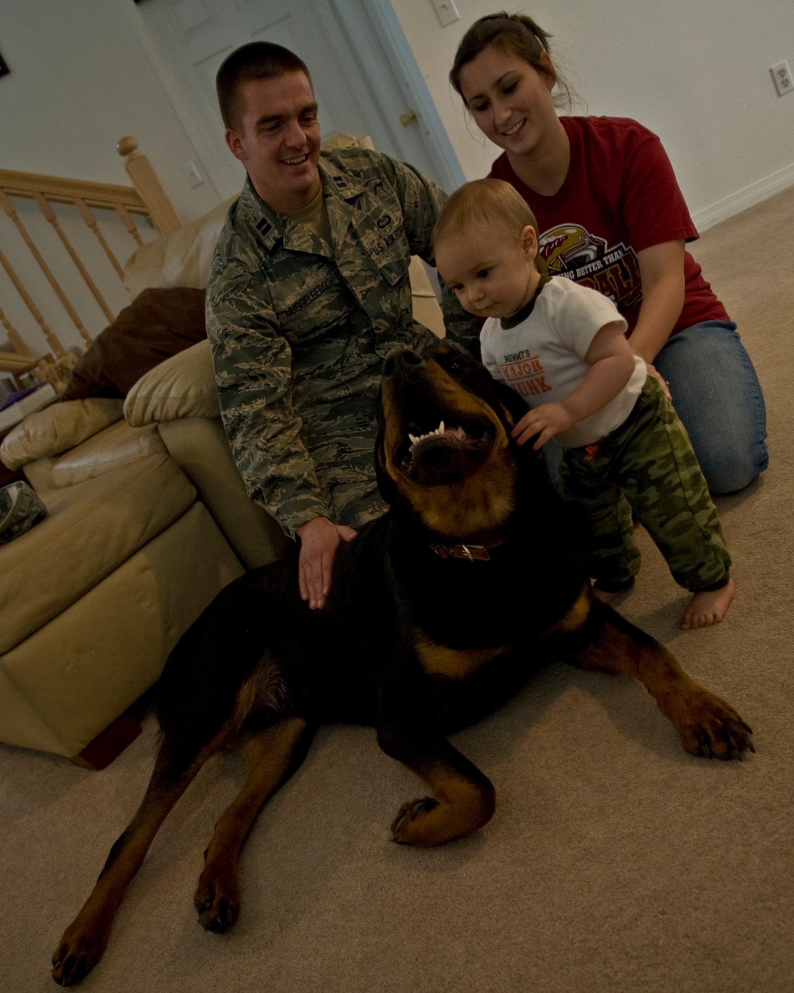 MOUNTAIN HOME AIR FORCE BASE, Idaho – The 366th Operation Support Squadron’s Weather Flight Commander, Capt. Daniel Muggelberg, his wife, Crystal, and son, James, play in the living room of their base house with Muggsy, a 130-pound Rottweiler.  Rottweiler’s are one of the breeds of dogs deemed “aggressive or potentially aggressive” under a new Air Force policy, and are now prohibited on base.    (U.S. Air Force photo by Staff Sgt. Roy Lynch III)