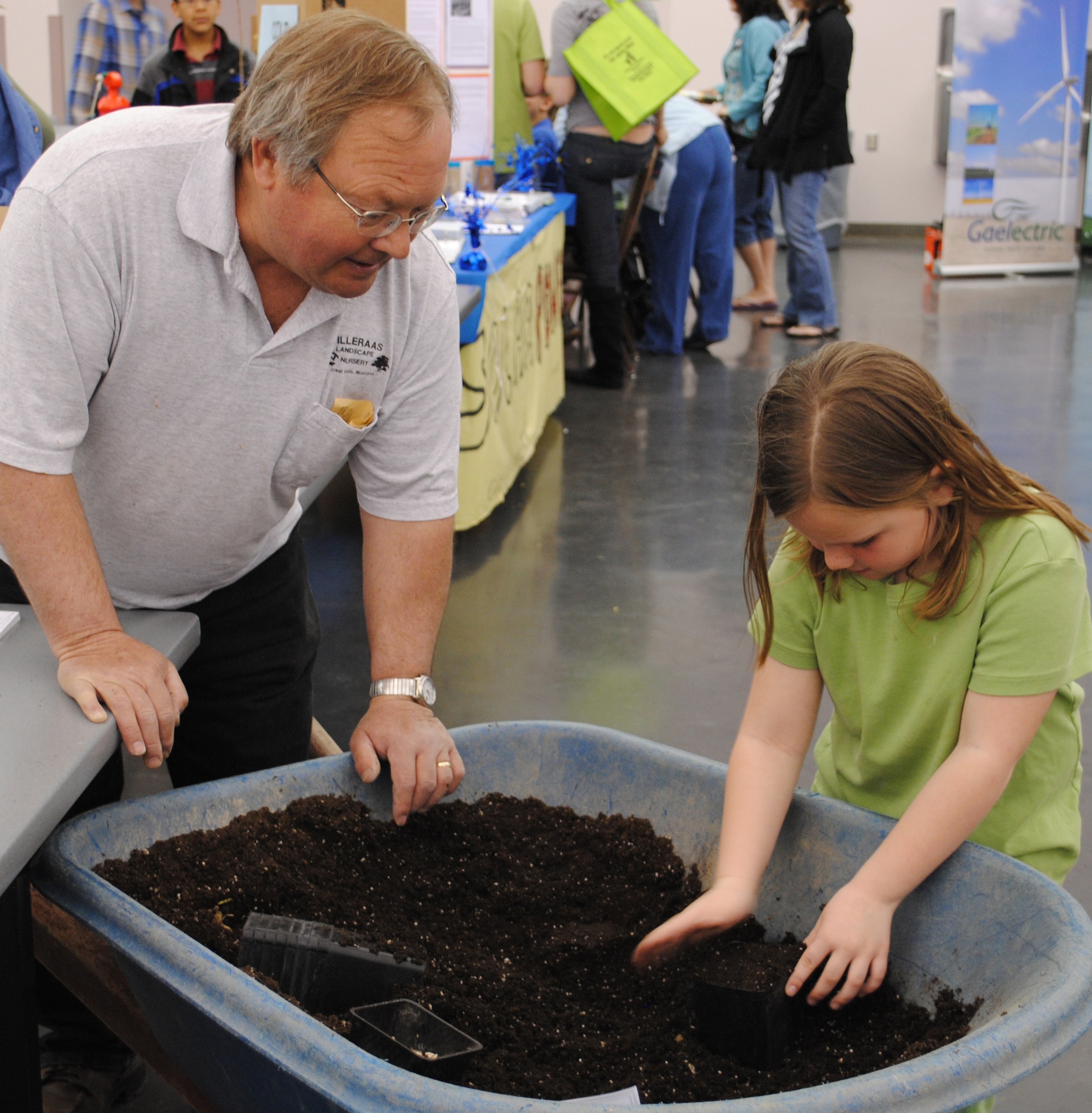 Steve Tilleraas, owner of Tilleraas Landscape Nursery, shows Kaycia Aldrich, 7, how to plant a sunflower.  The annual Earth Day celebration had several activities for children.  (U.S. Air Force photo/Airman Cortney Hansen)