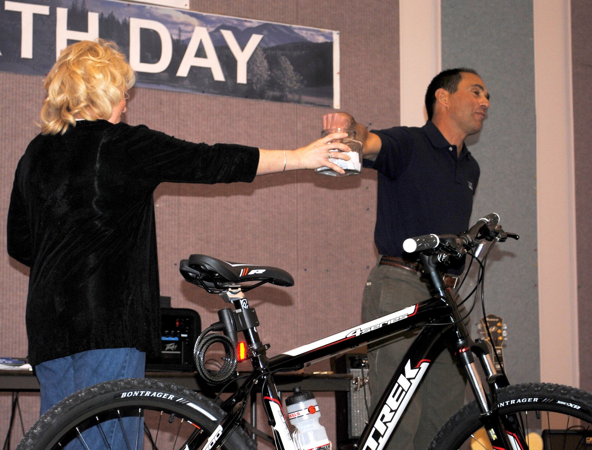 Debbie Kimball, a representative of the City of Great Falls, holds a jar full of Earth Day poster contest participants' names while Mark Bell, principal client service manager at Weston Solutions, drawsthe winning entry.  The Trek bike, valued at $500, was given away along with bike accessories at the Earth Day celebration.  (U.S. Air Force photo/Airman Cortney Hansen)