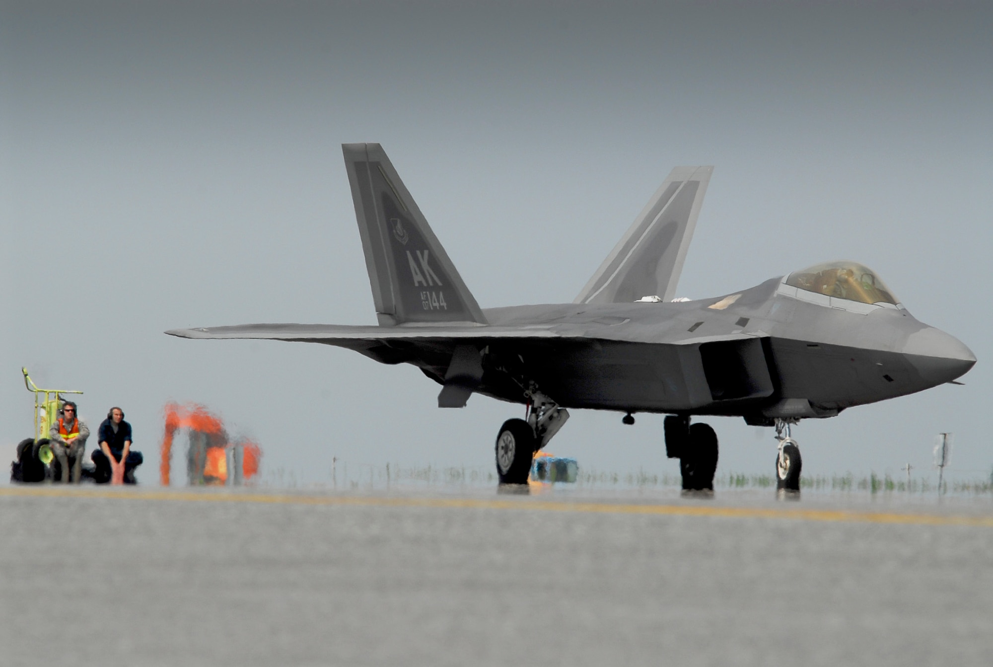 Airmen watch as an F-22 Raptor taxis toward a refueling station March 31, 2011, on the flightline at Kadena Air Base, Japan. The pilots and maintainers, along with the F-22s, are assigned to the 525th Expeditionary Fighter Squadron at Joint Base Elmendorf-Richardson, Alaska. They deployed to Kadena AB earlier in 2011 to test their capabilities in a new environment and to train with Airmen and aircraft there. (U.S. Air Force photo/Airman 1st Class Maeson L. Elleman)