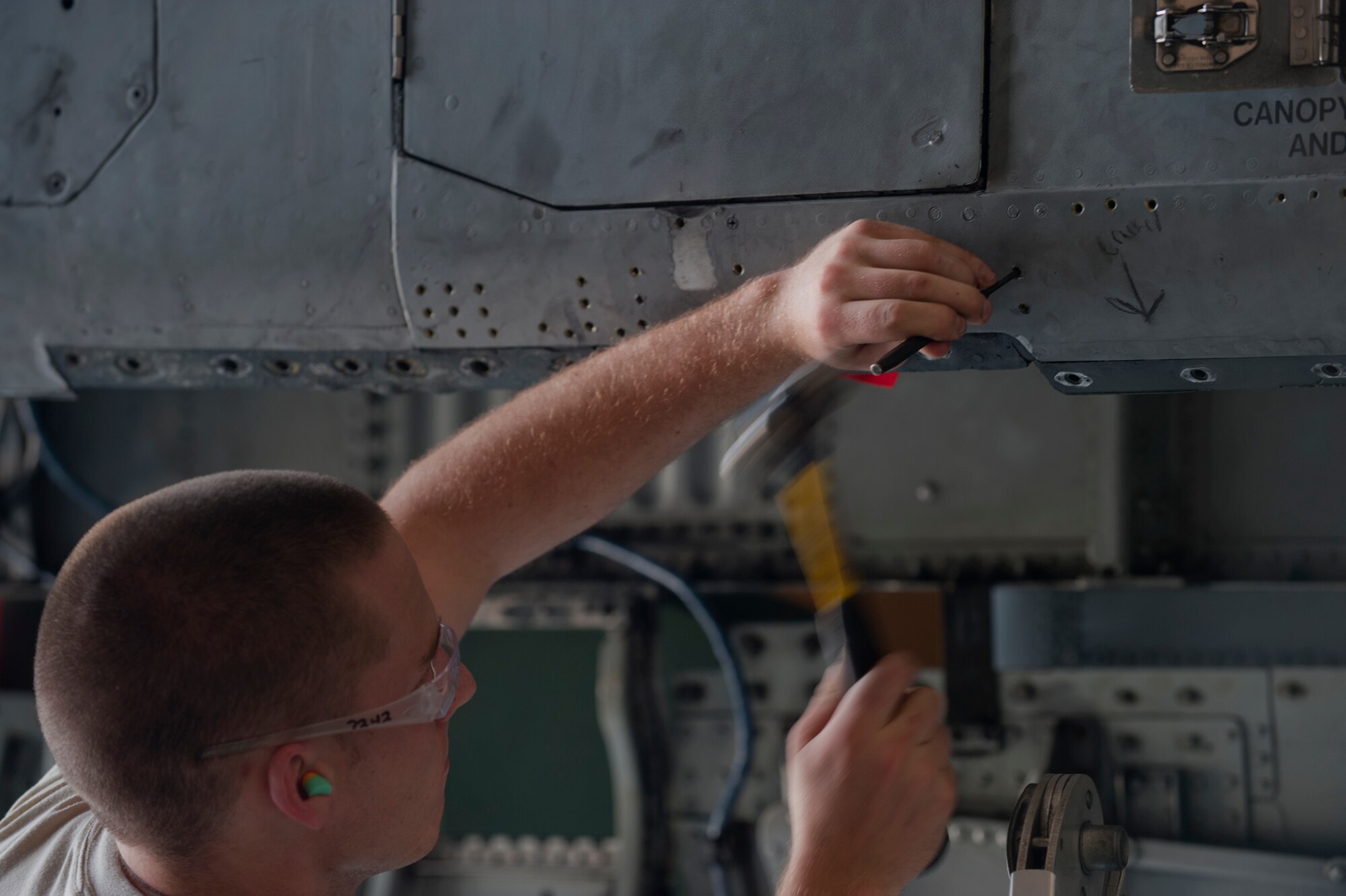 Airman 1st Class Connor Minto, 23rd Equipment Maintenance Squadron aircraft structural maintenance apprentice, drives out a rivet from a panel on an A-10C Thunderbolt II at Moody Air Force Base, Ga., April 20. After all of the rivets were removed, the panel was removd. (U.S. Air Force photo/Airman 1st Class Douglas Ellis)(RELEASED)
