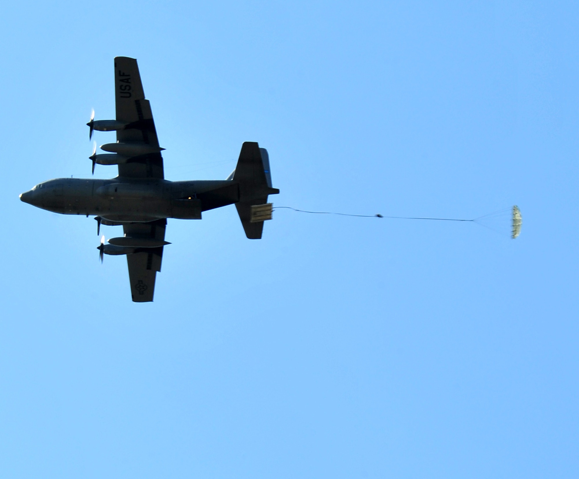 A C-130 drops cargo April 13, 2011, over the Black Jack drop zone, north of Little Rock Air Force Base, Ark., during the combat surge week. The purpose of the surge week was to make up for lost flying time by increasing the operations tempo. (U.S. Air Force photo by Airman 1st Class Rusty Frank)