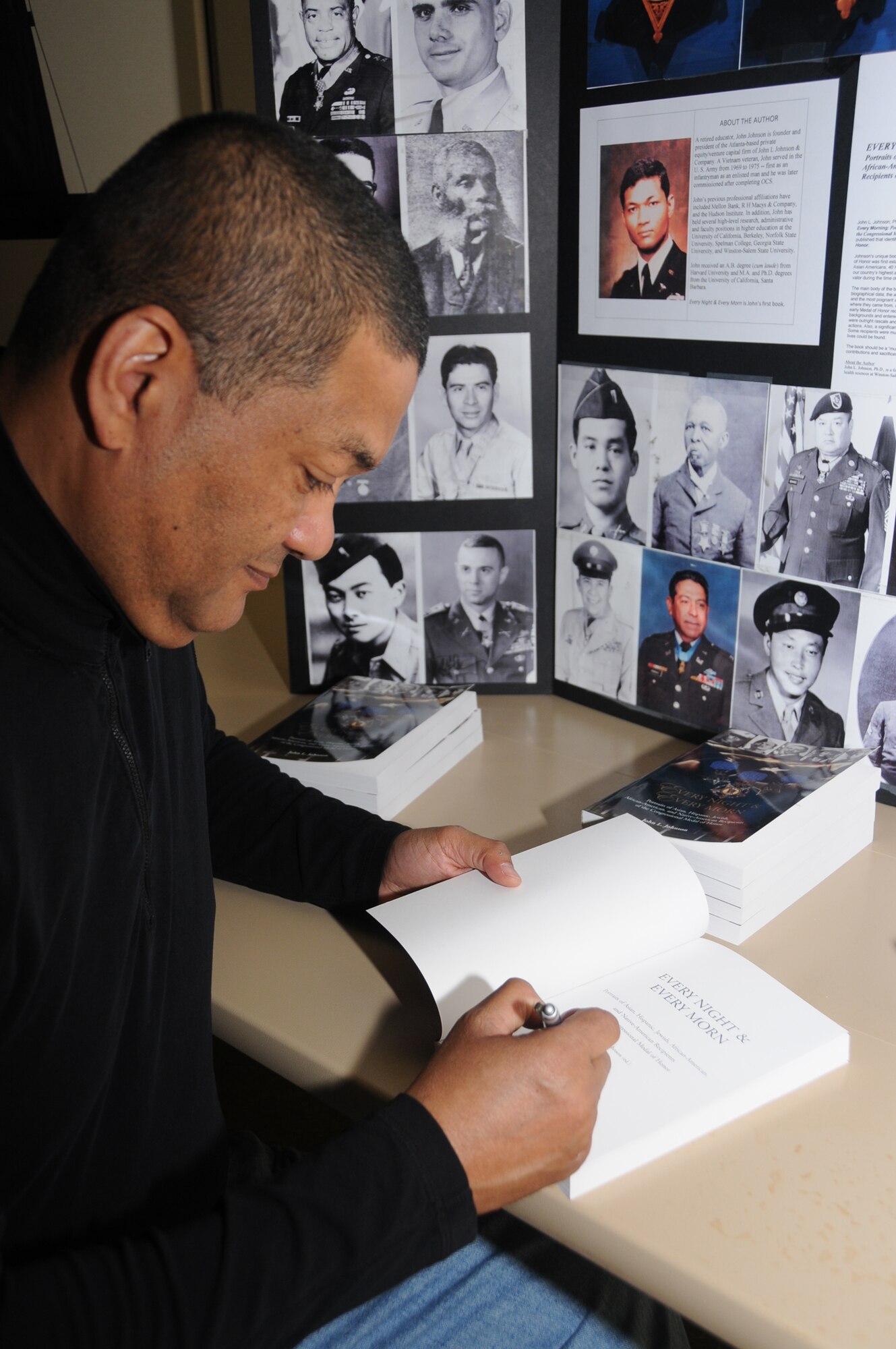 Author John L. Johnson signs a copy of his book, “Every Night & Every Morn: Portraits of Asian, Hispanic, Jewish, African-American and Native-American Recipients of the
Congressional Medal of Honor,” April 11 at the Bay Breeze Event Center. The medal is the highest military decoration awarded by the U.S. government. Mr. Johnson’s visit was part of Keesler’s observance of National Library Week.  (U.S. Air Force photo by Kemberly Groue)