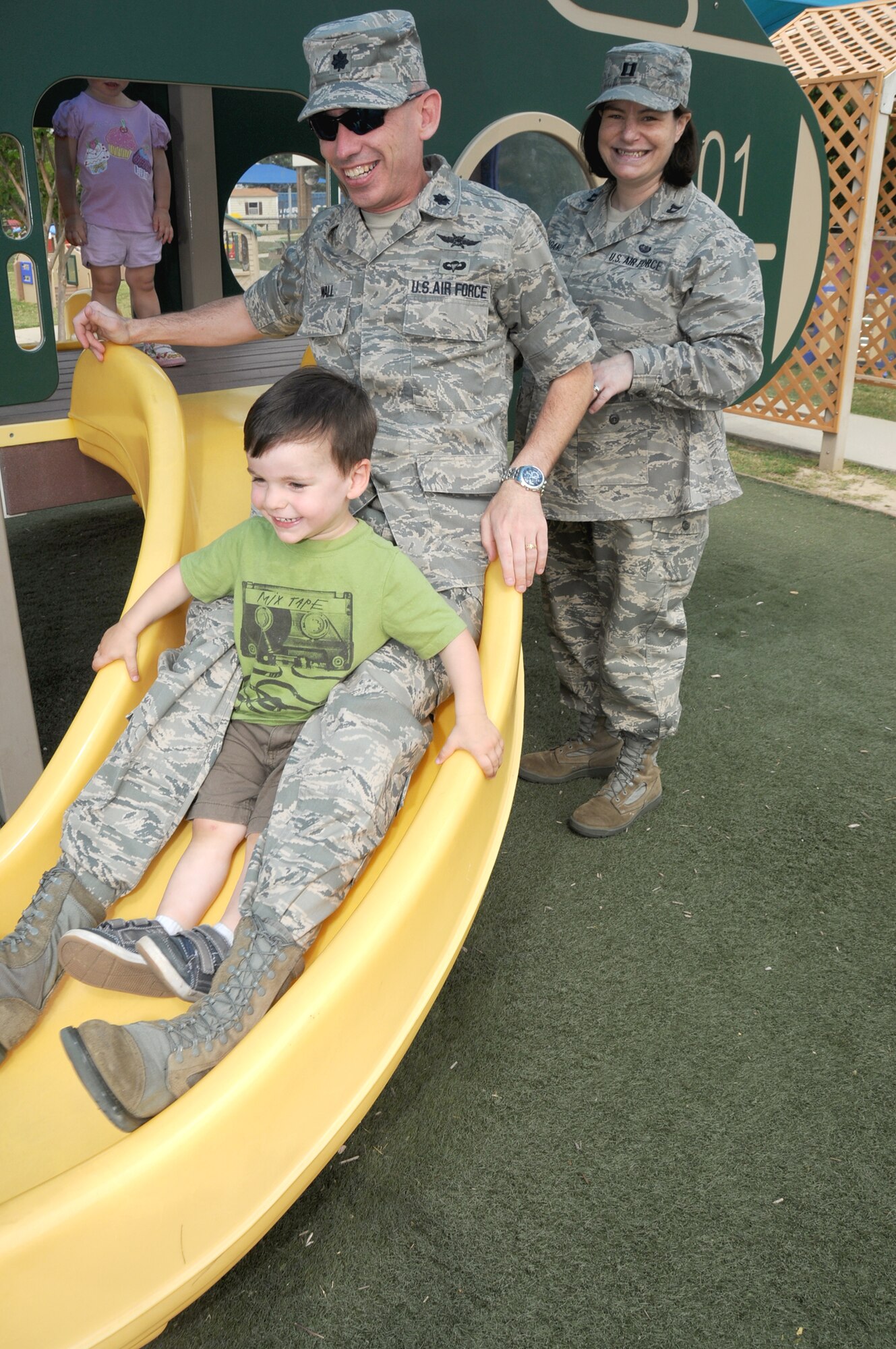 Lt. Col. Trevor Wall, 332nd TRS commander, takes a short ride down the slide with his son Alex, 2. His wife, Capt. Rhea Lagano, 2nd Air Force, looks on.  (U.S. Air Force photo by Kemberly Groue)