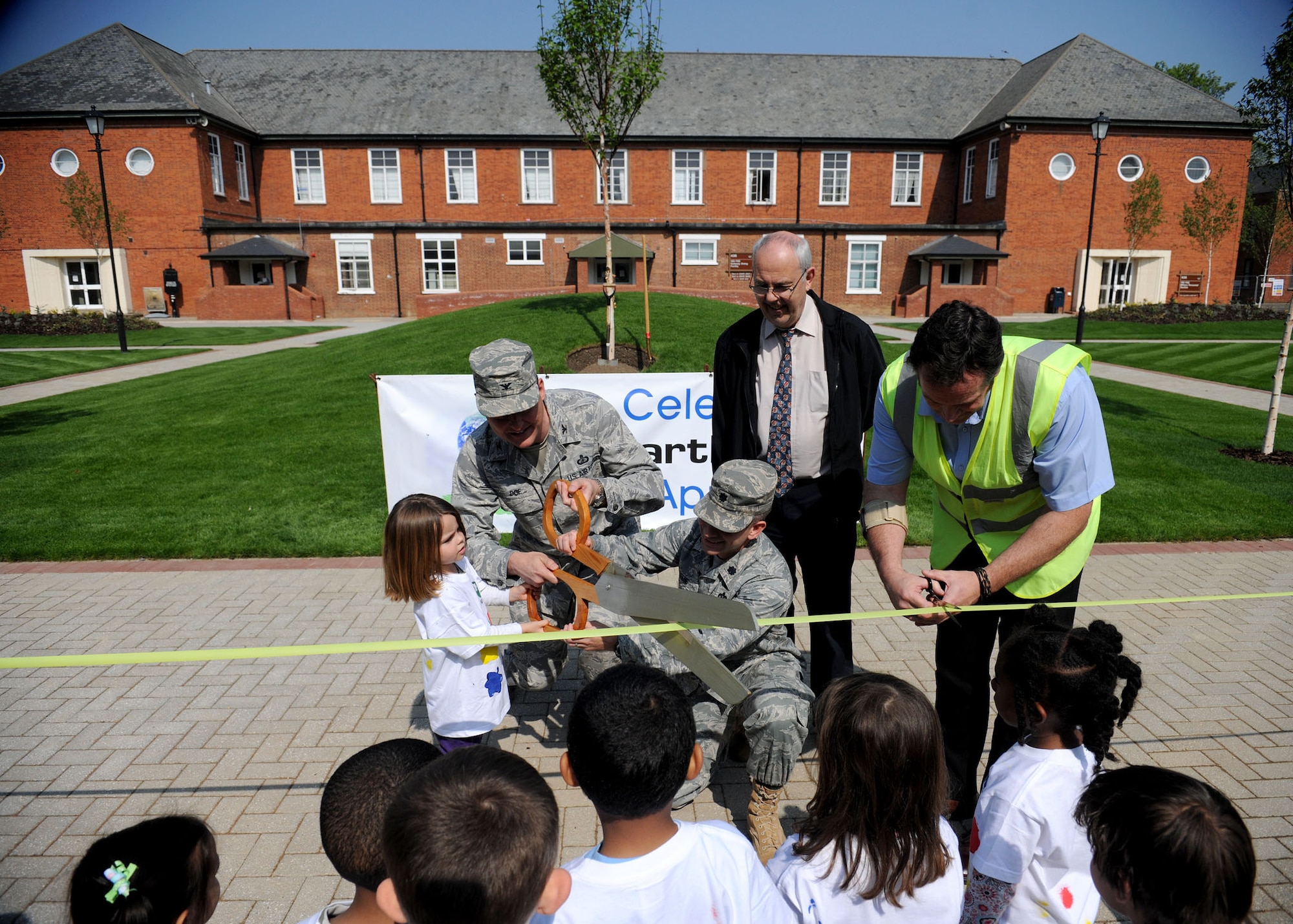 RAF MILDENHALL, England -- Shannon,5, daughter of Robert and Samantha  Webb, 48th Security Forces Squadron, Col. David Doe, 100th Mission Support Group commander, and Lt. Col. Matt Greene, 100th Civil Engineer Squadron commander, cut the ribbon during the grand reopening of Washington Square April 20, 2011. The former parking lot was transformed into a pedestrian area, to include bench seating, walkways and nearly 20 newly planted trees. (U.S. Air Force photo/Staff Sgt. Jerry Fleshman)